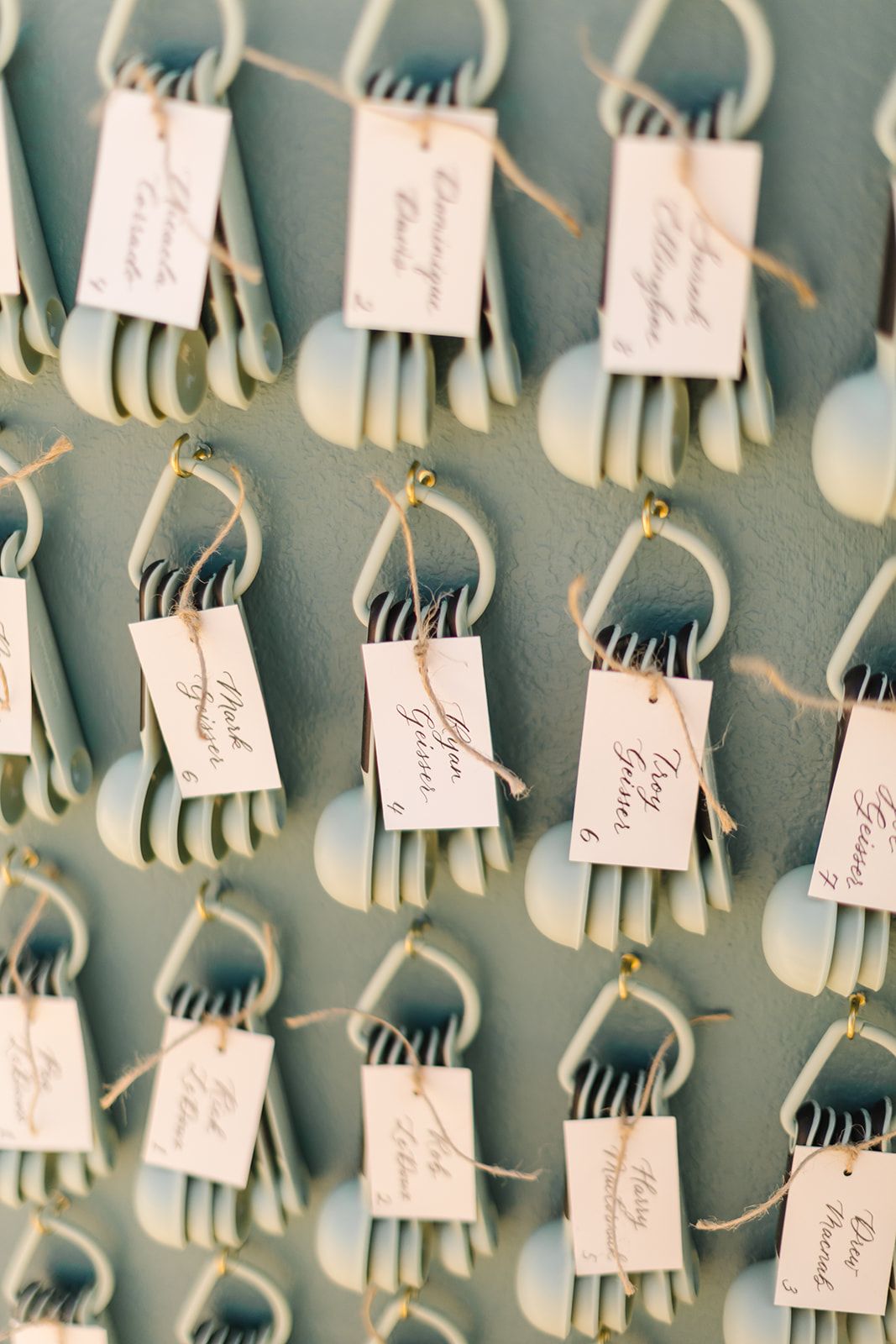 Wedding place cards with silverware attached displayed in organized grid pattern.