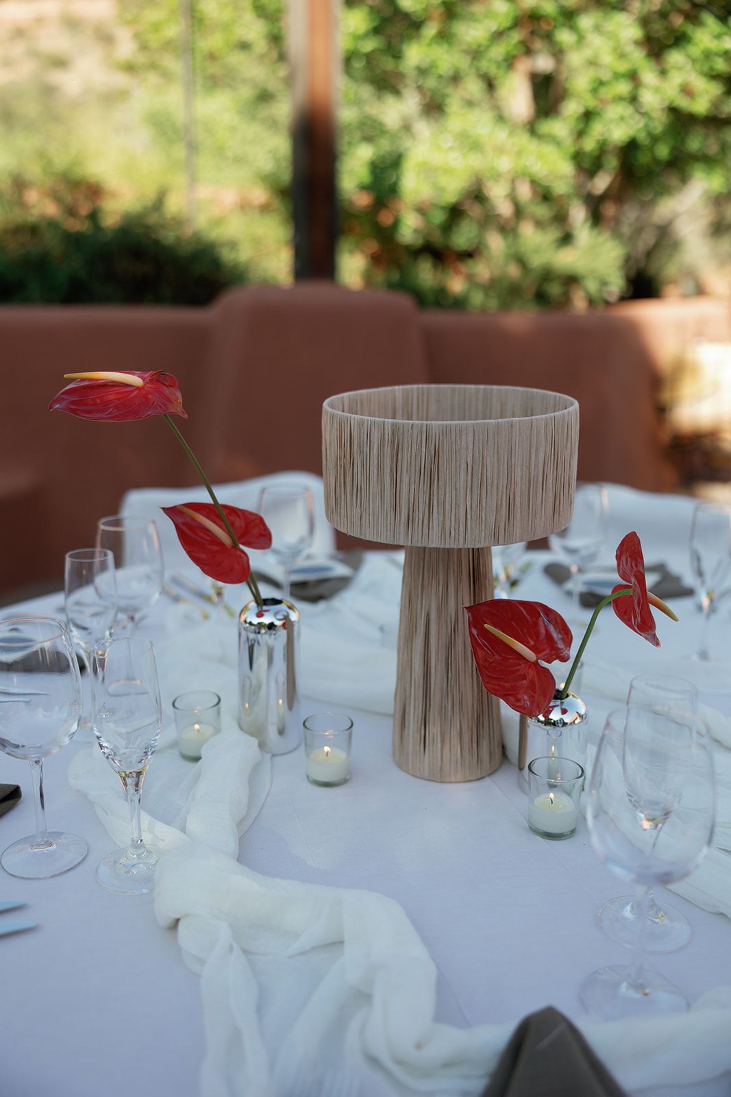 Elegant table setting with zen-inspired beige centerpiece and red anthurium flowers on crisp white tablecloth.