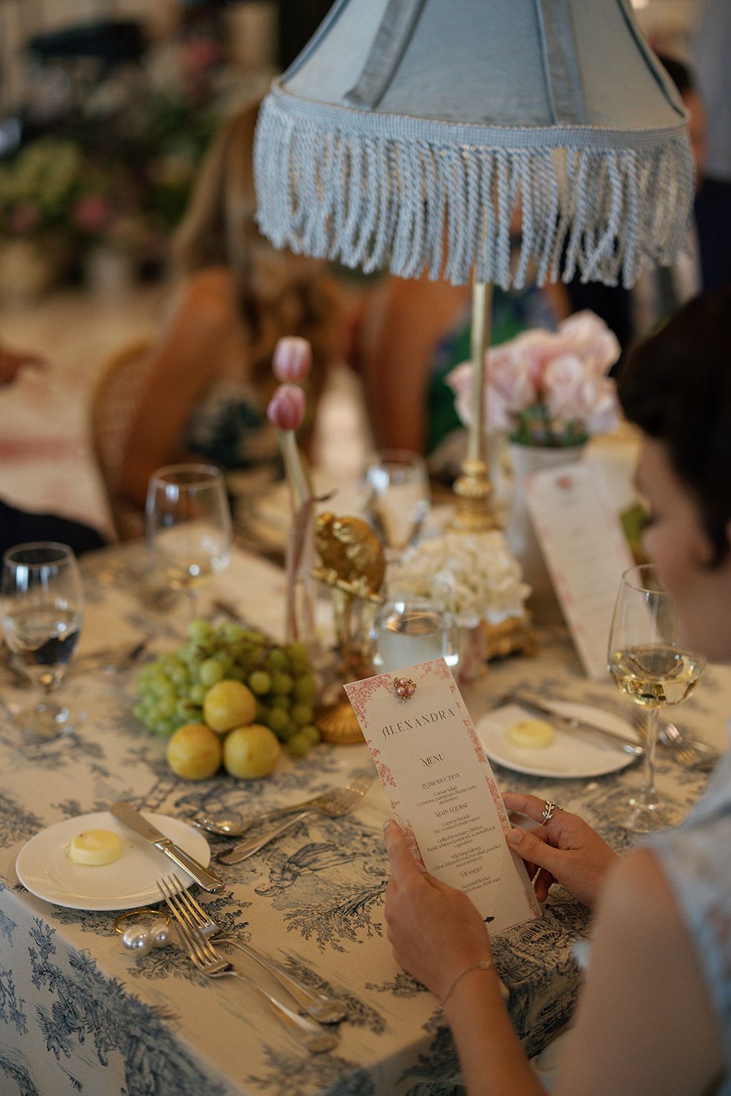 Wedding table settings with blue and white toile tablecloth, place cards, and green apples as decor elements.
