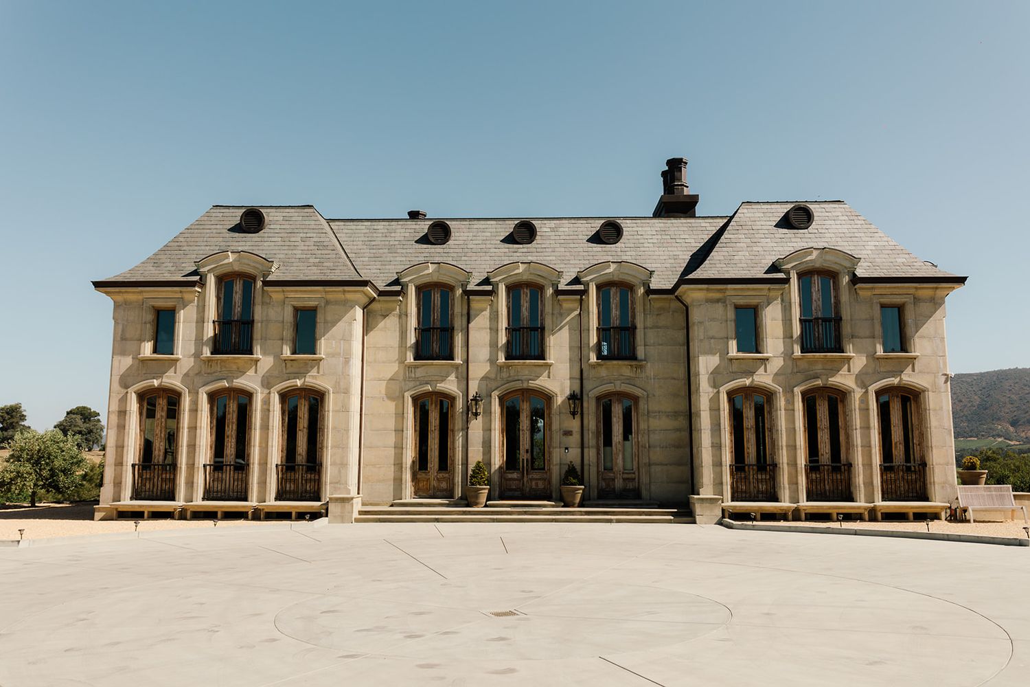 Large symmetrical stone mansion with multiple dormer windows and classical architecture.