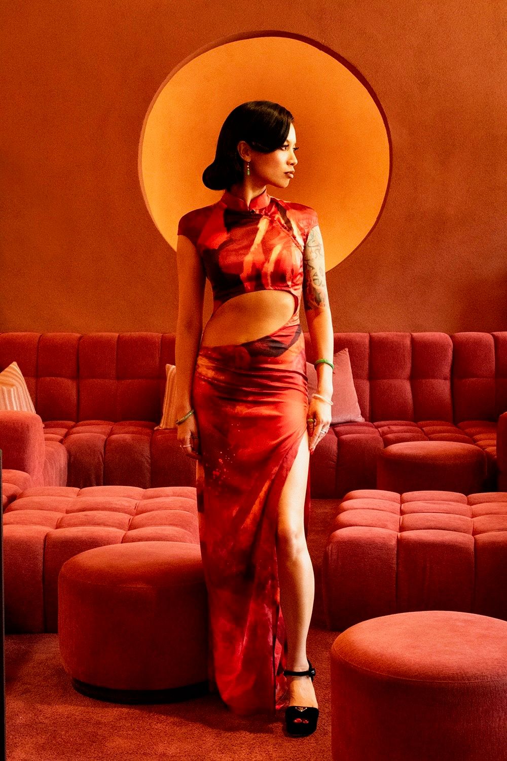 A series of red-tinted photographs showing a figure in a red dress posed against curved theater seating.