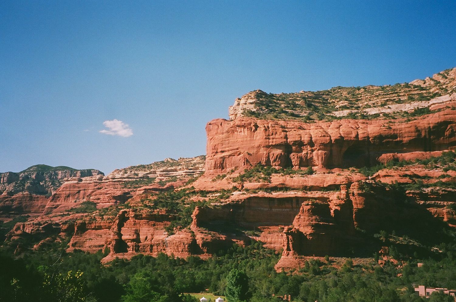 Stunning panoramic view of red rock formations and sandstone cliffs in Sedona against bright blue Arizona skies.
