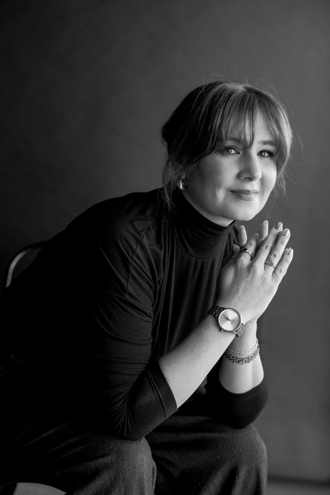 A series of black and white portraits showing contemplative poses in dramatic lighting with hands near the face.