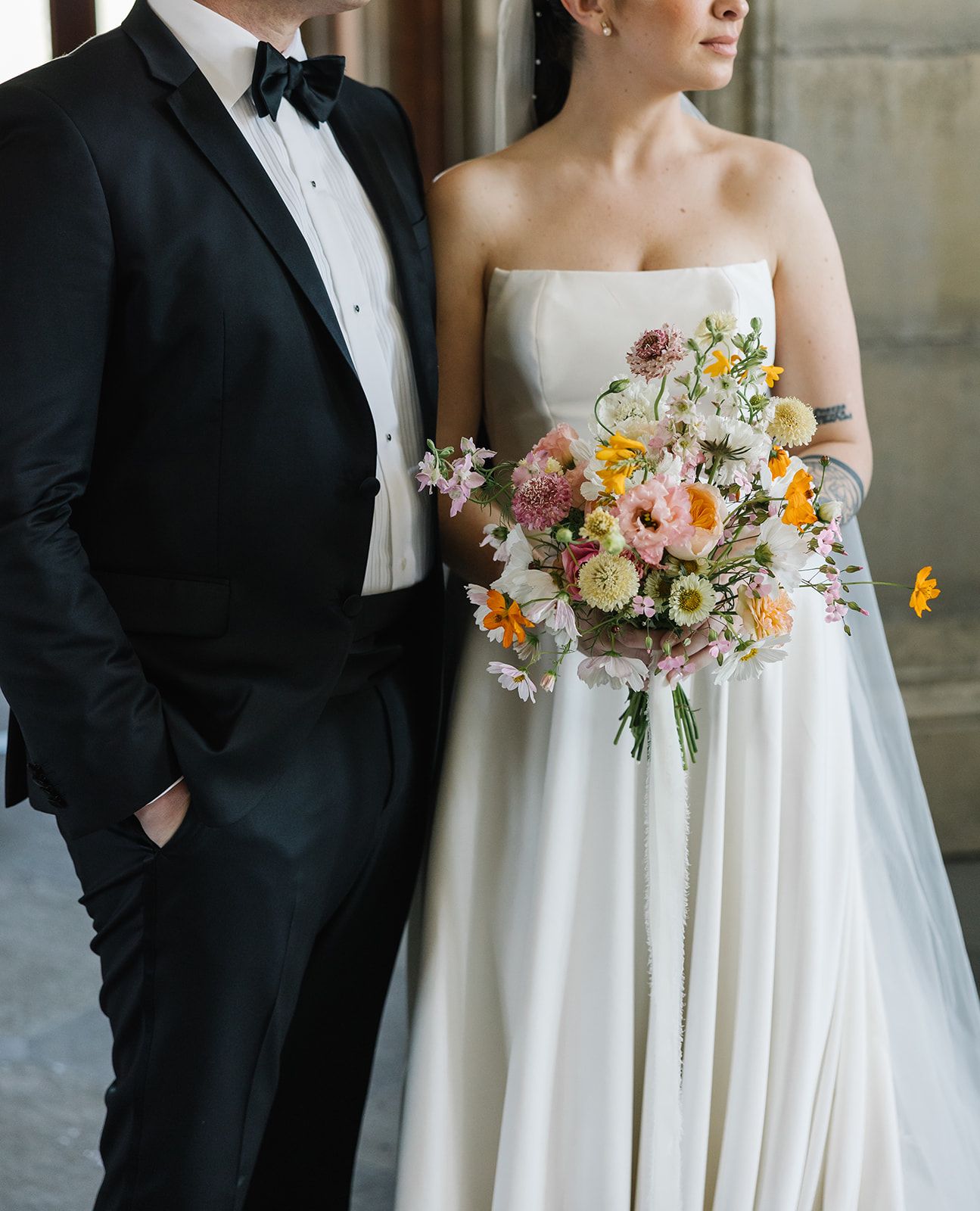 Classic wedding portrait showing elegant bridal bouquet with colorful spring flowers against white dress.