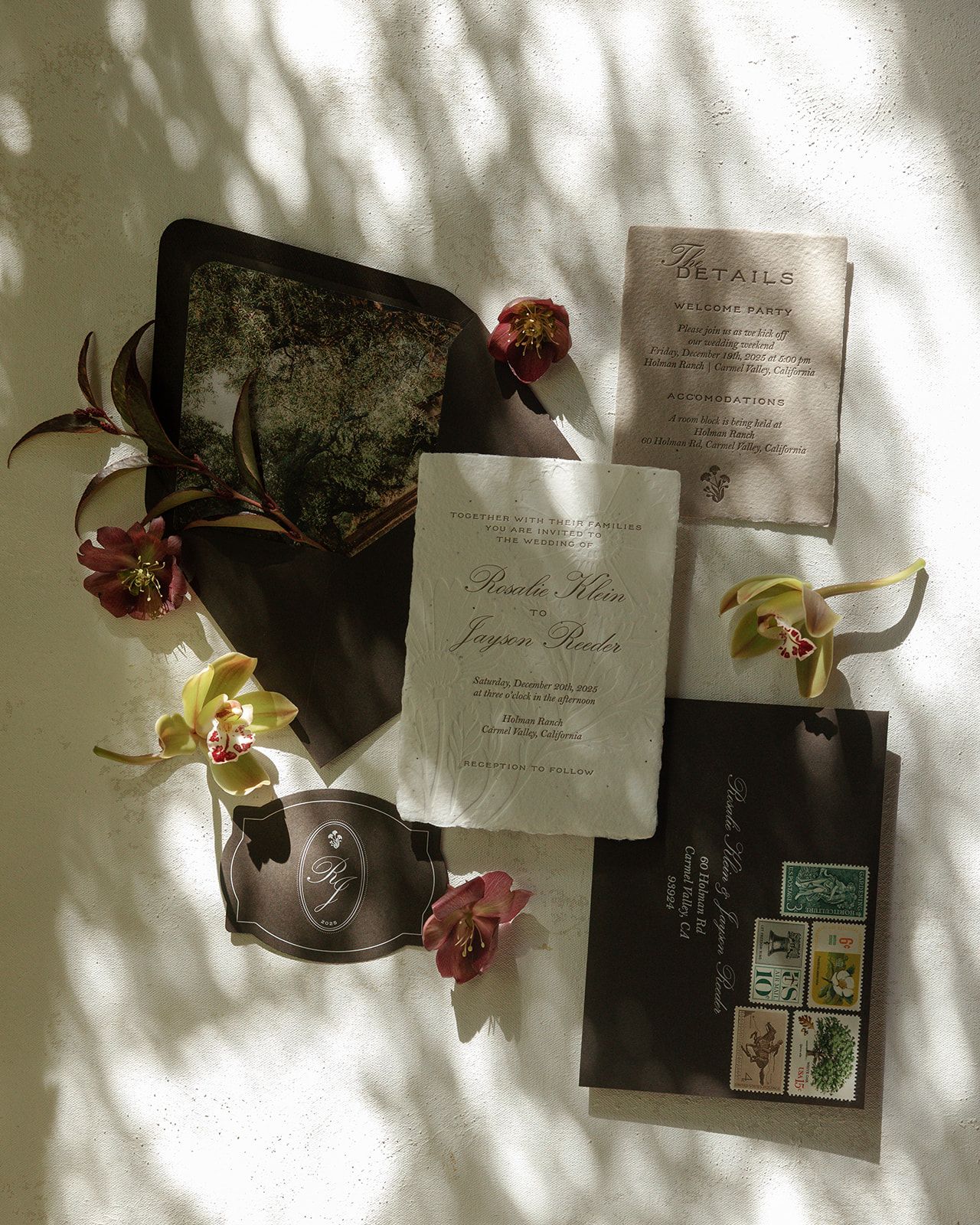 Wedding invitation cards and orchid flowers arranged artistically against a sunlit wall with shadow patterns.