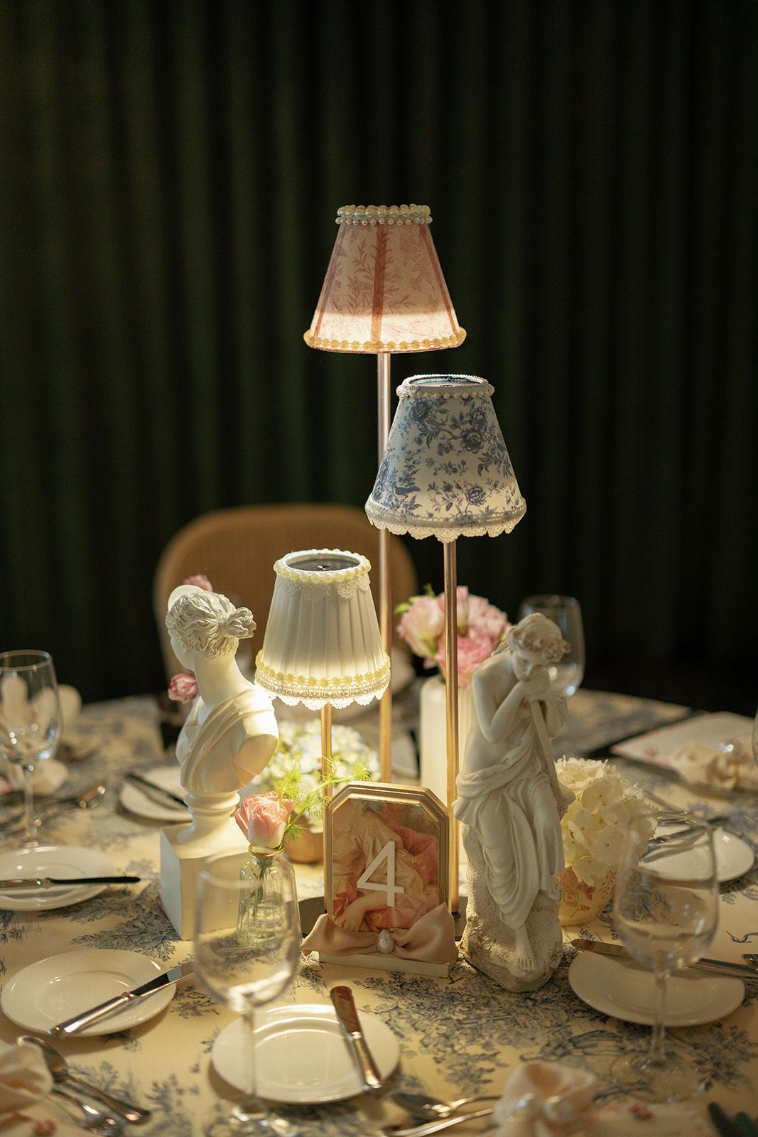 Elegant wedding reception table settings with glowing lampshades and white china plates create a romantic atmosphere.