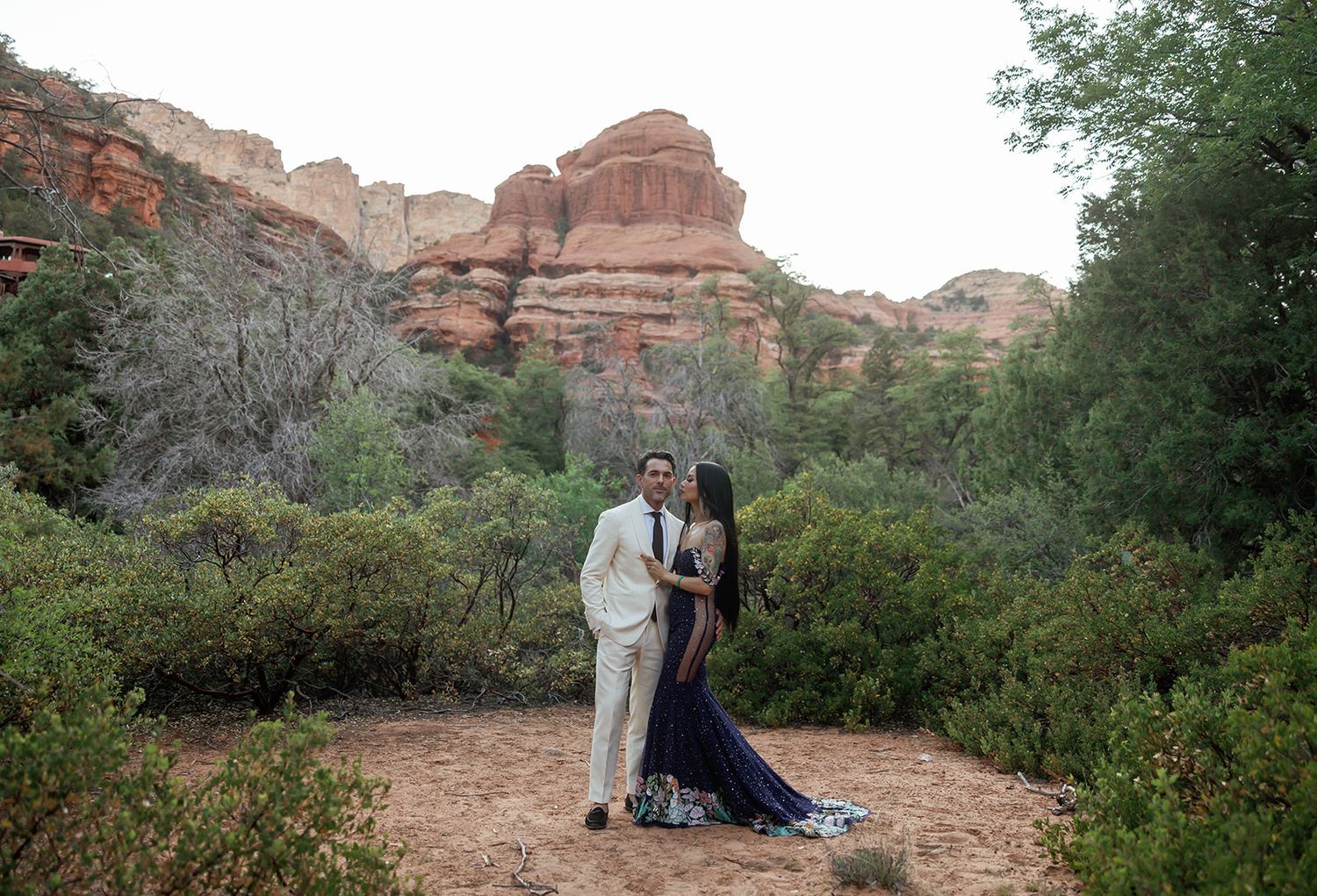 Couple shares a romantic moment against stunning red rock formations in Utah's scenic desert landscape.