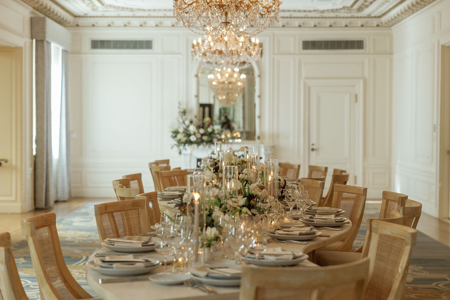 Luxurious dining room with crystal chandelier and round table set for an elegant celebration.