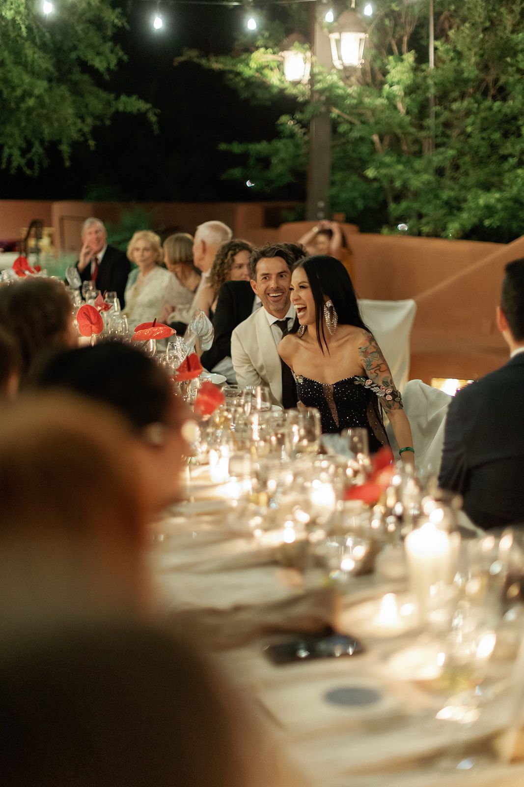 Evening dinner party with candlelit tables, string lights overhead and elegant table settings creating a romantic ambiance.