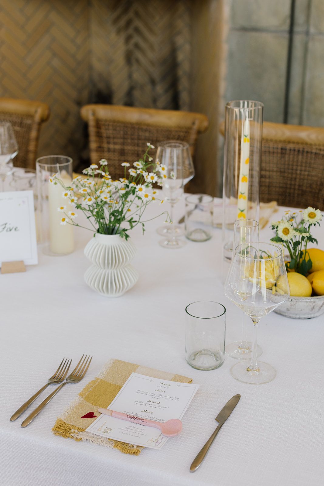 Minimalist table setting with white floral centerpiece, lemons and place settings.