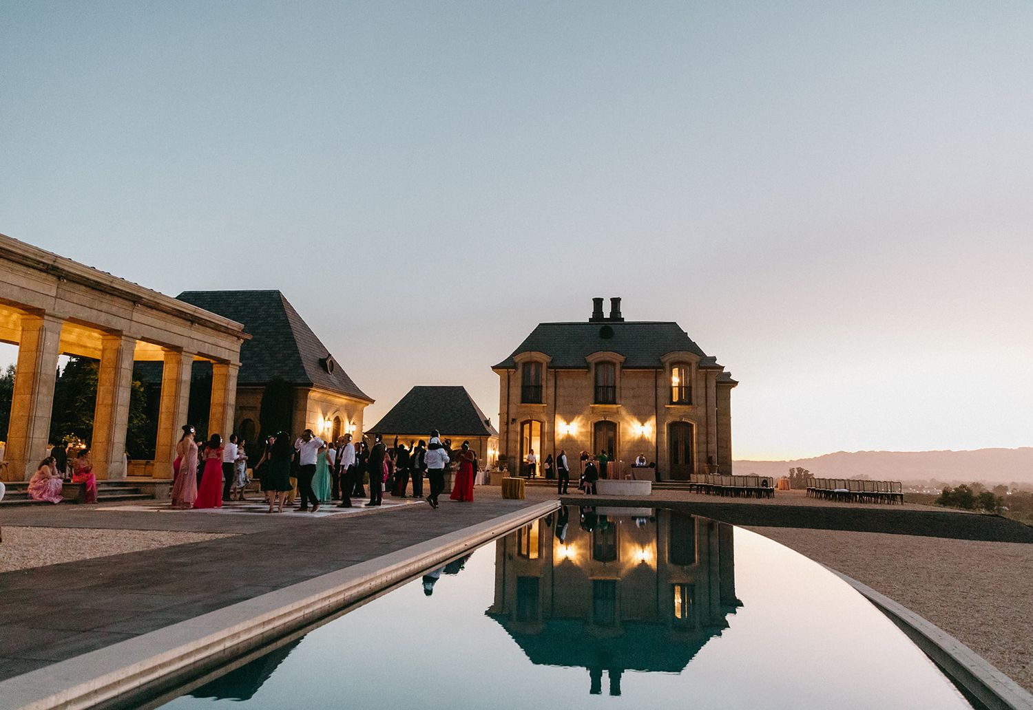 Luxurious venue with reflecting pool and elegant architecture at sunset during wedding celebration.