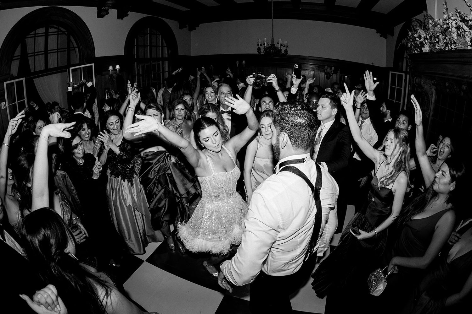 Energetic crowd of people dancing and jumping at a lively nightclub event, captured in black and white photography.