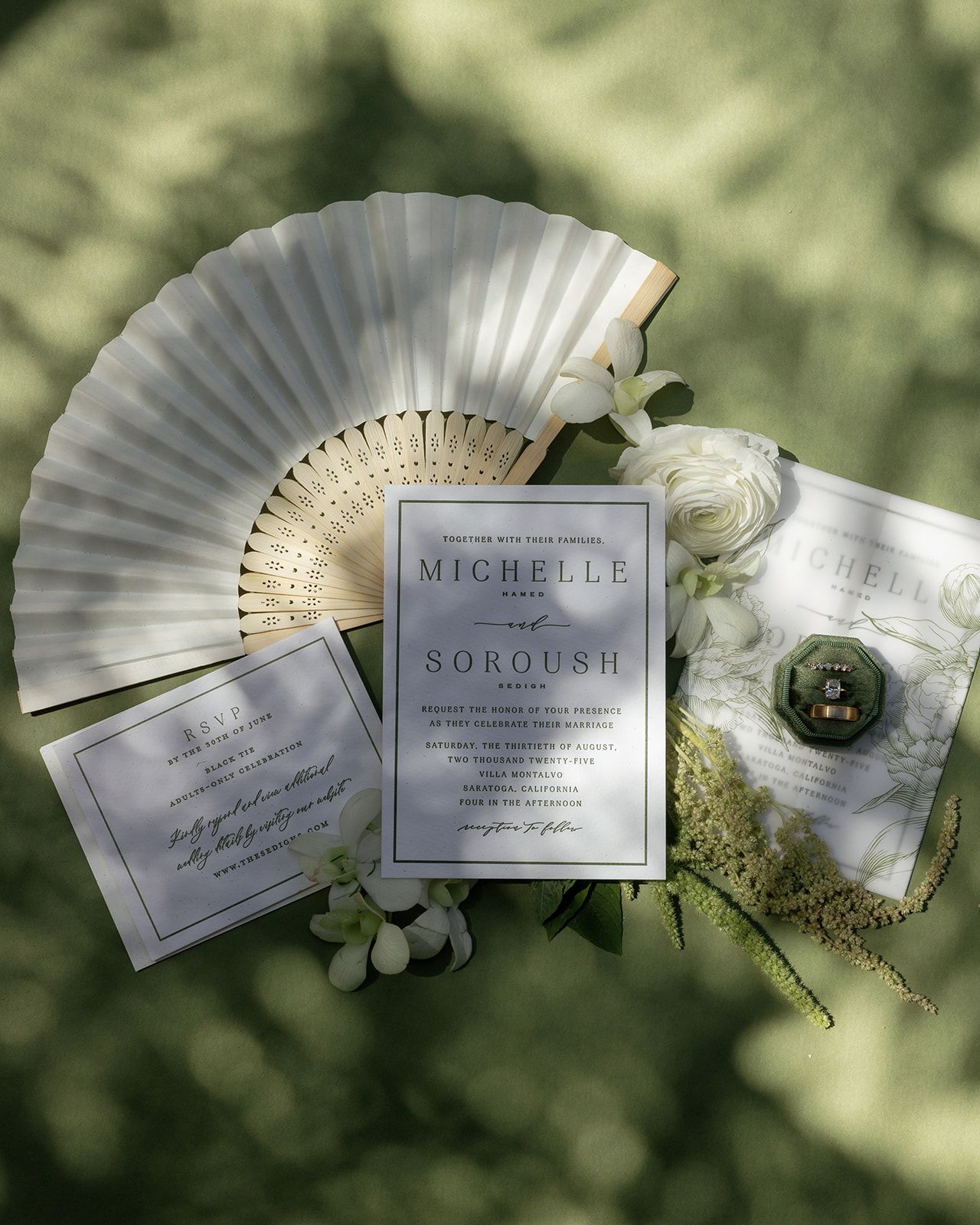Elegant wedding invitations and paper fans arranged artistically against a soft green bokeh background.