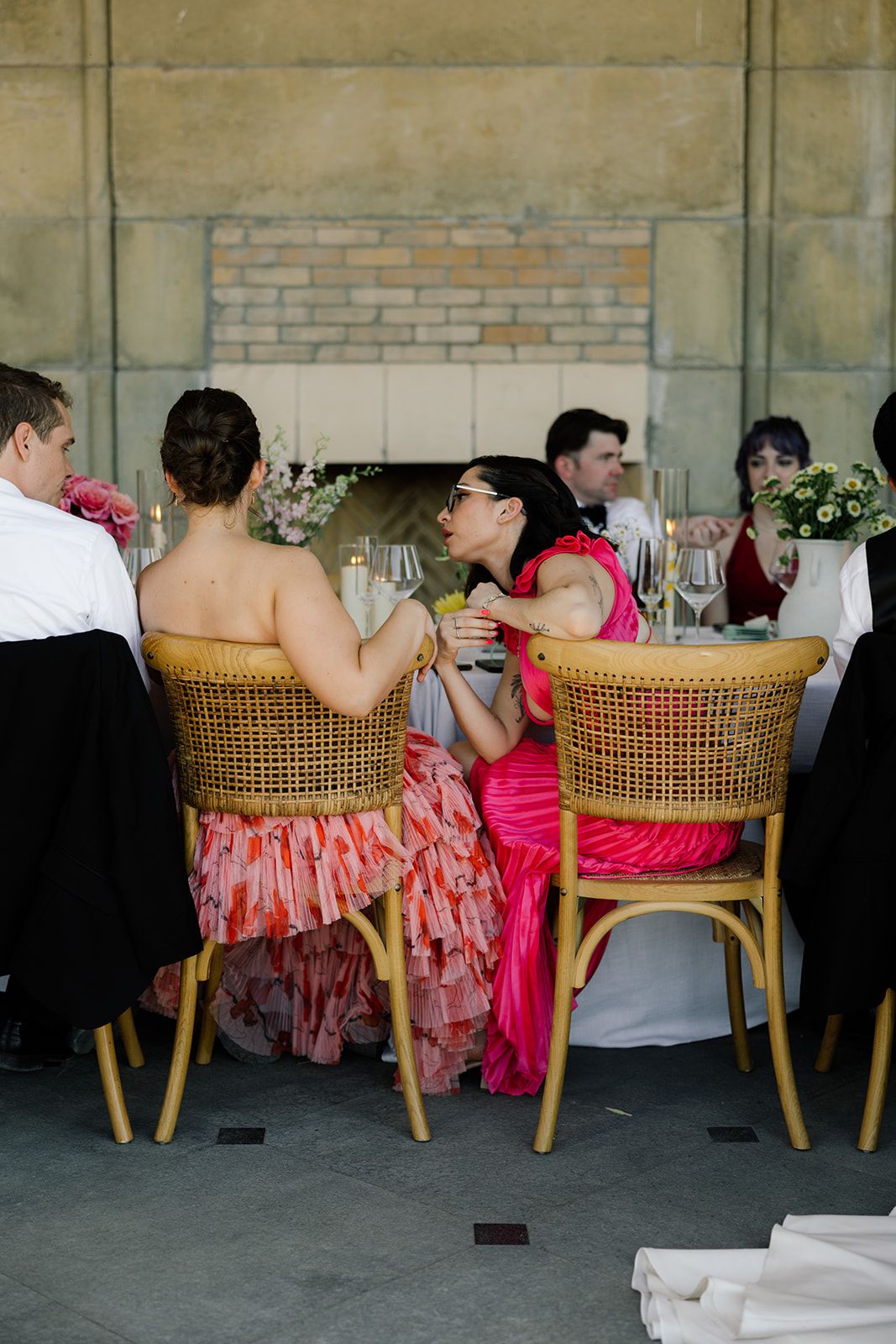 Wedding guests enjoying conversation at outdoor reception with wicker chairs.