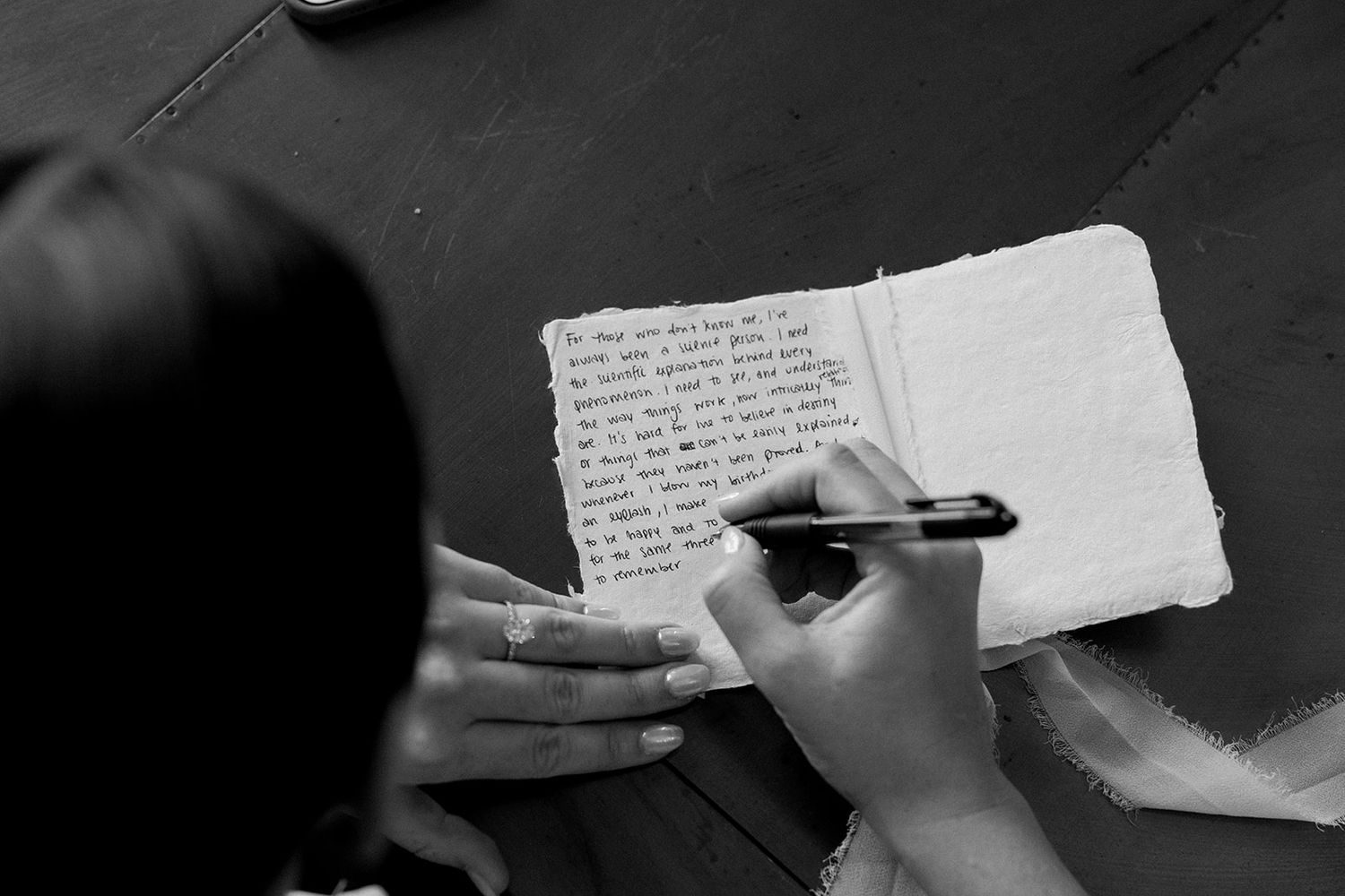 Hand writing personal notes on white paper in black and white.