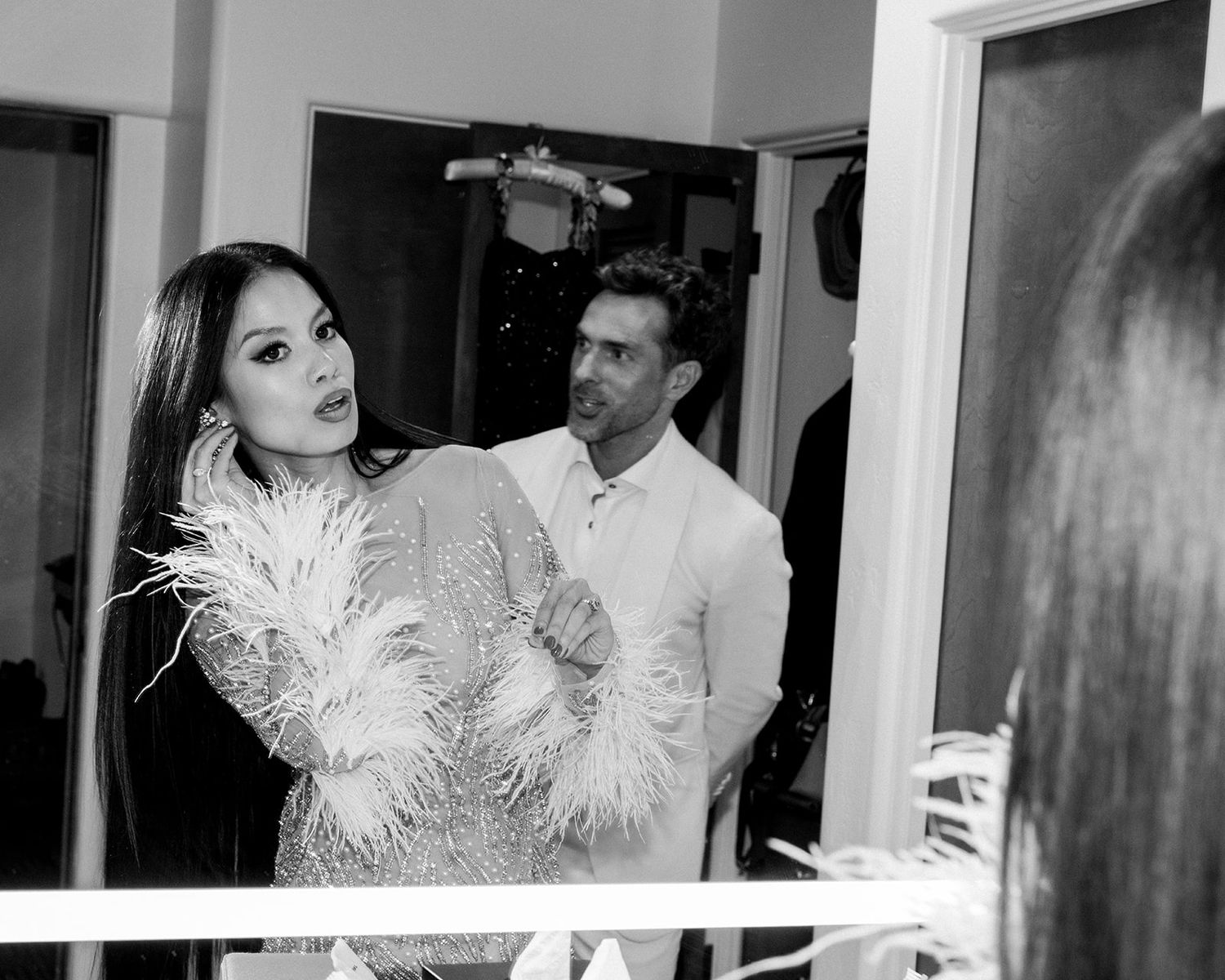Behind-the-scenes black and white photo at a fashion event showing models and crew preparing backstage.