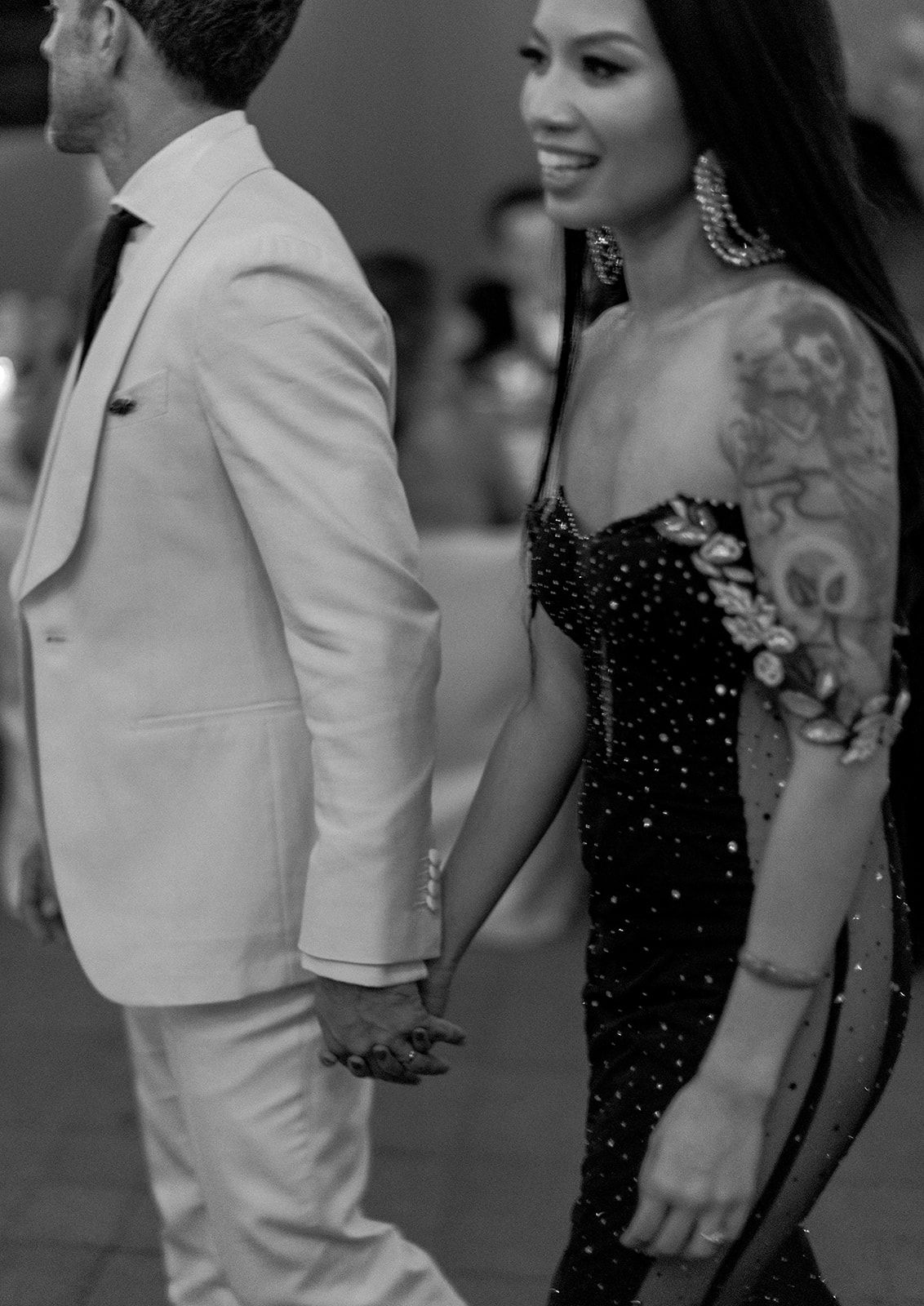 A couple dressed in formal black and white attire poses together at what appears to be an event or celebration.