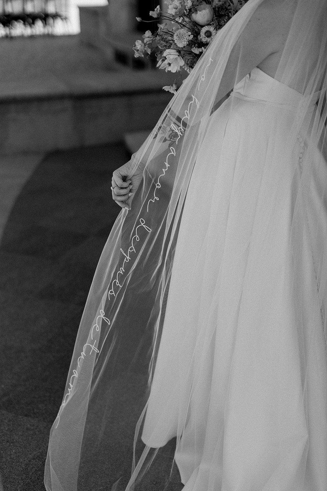 Close-up detail of intricate lace trim on a flowing white wedding veil in black and white.