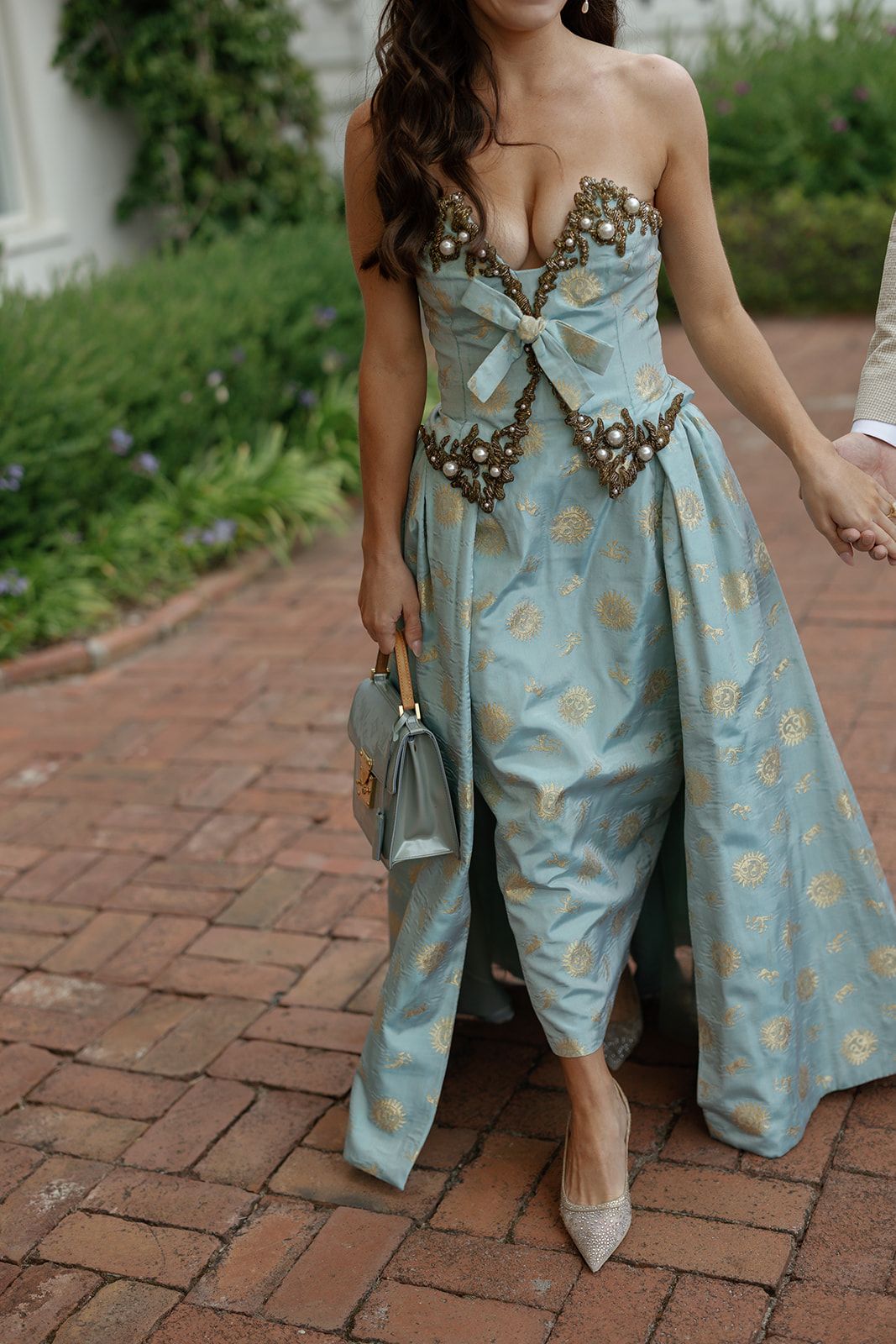 A light blue and gold floral jacquard dress is shown from different angles on brick pavement.