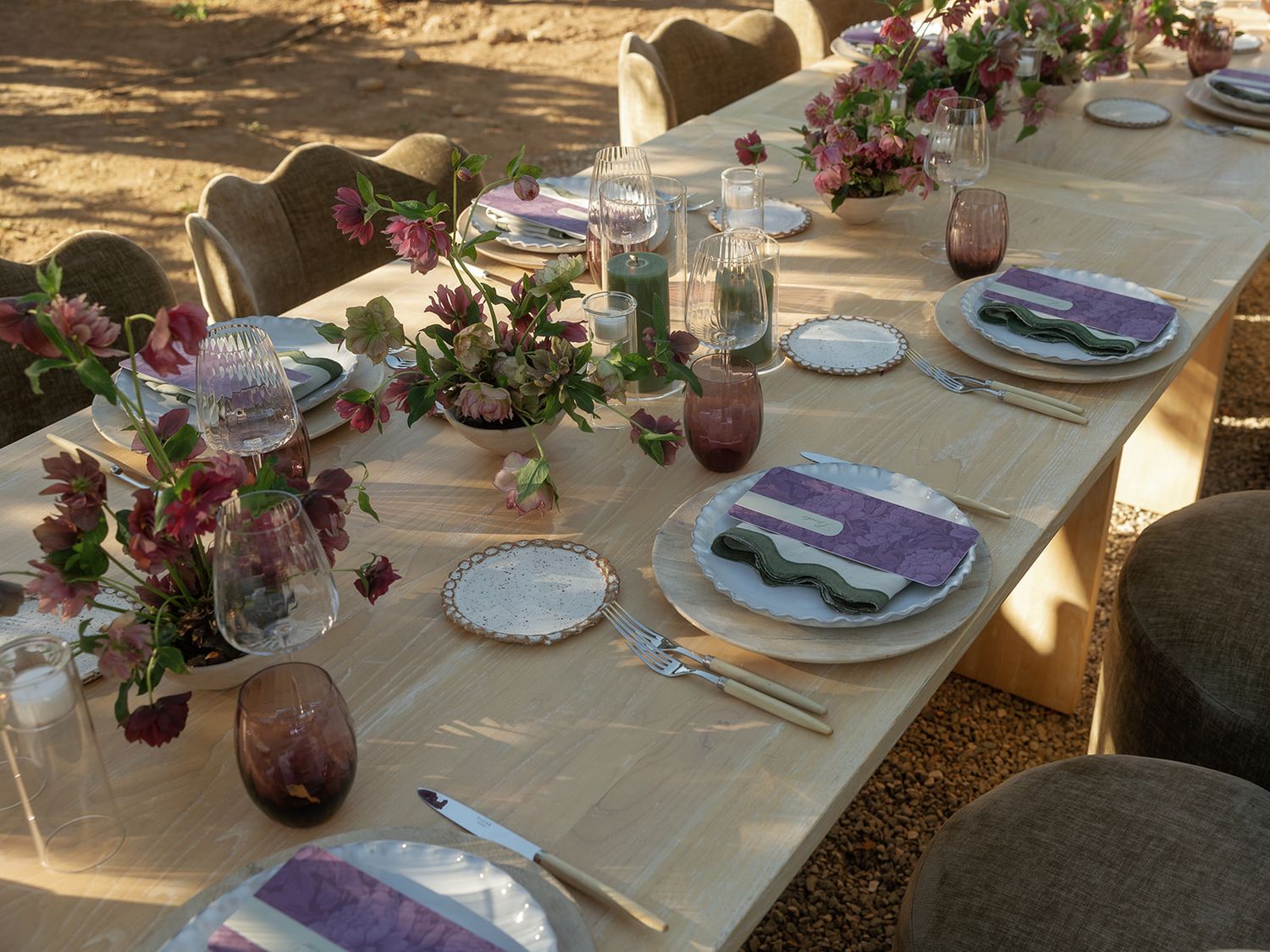Elegant outdoor dining table set with purple napkins, floral centerpieces, and lavender glassware for a desert wedding.