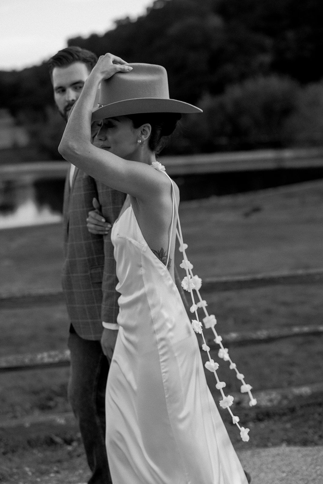 Black and white photo of a bride in a white dress holding and cowboy hat. Western Rehearsal Dinner.