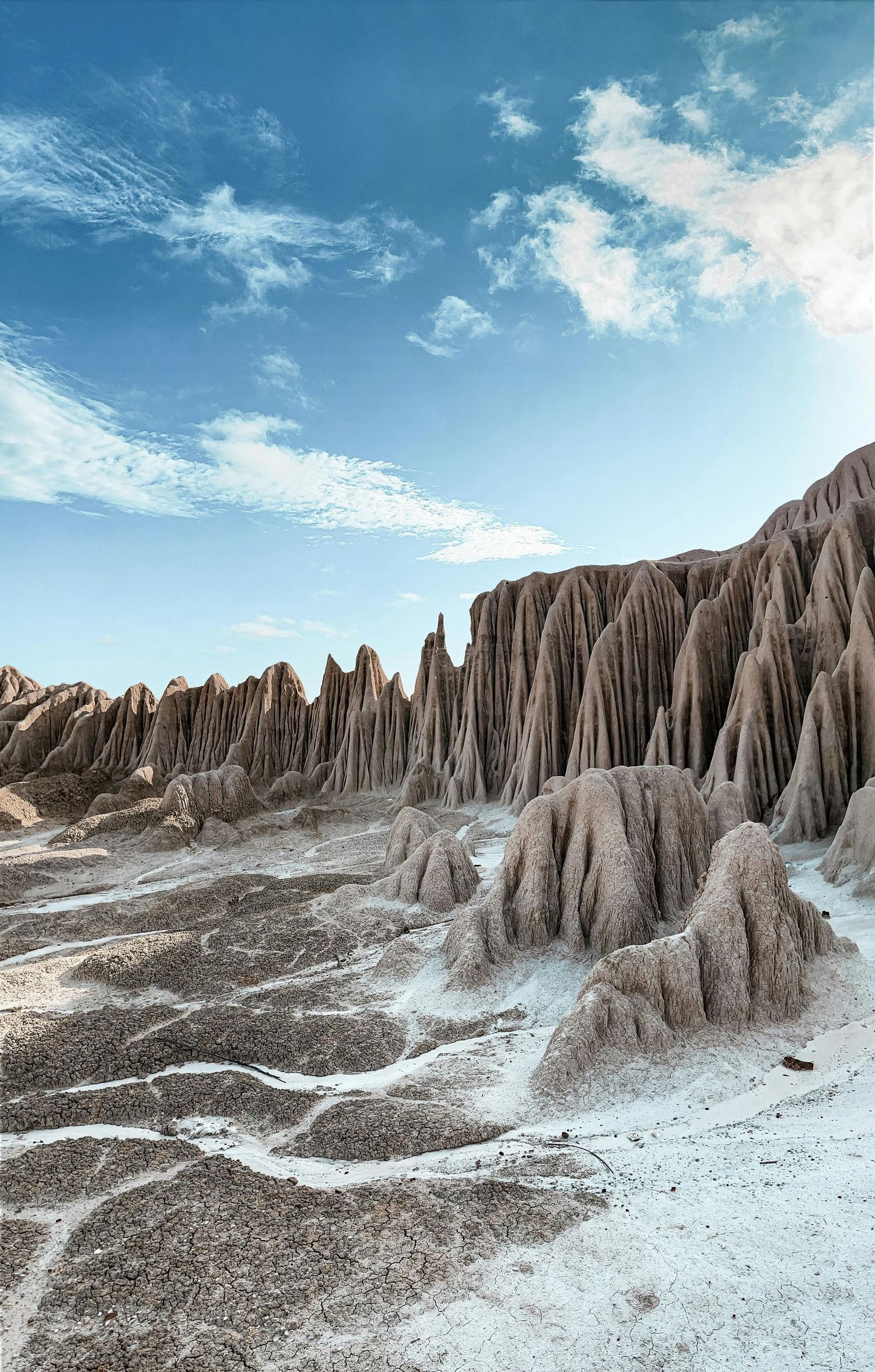 Eroded desert badlands with dramatic ridges and textures under a bright blue sky.