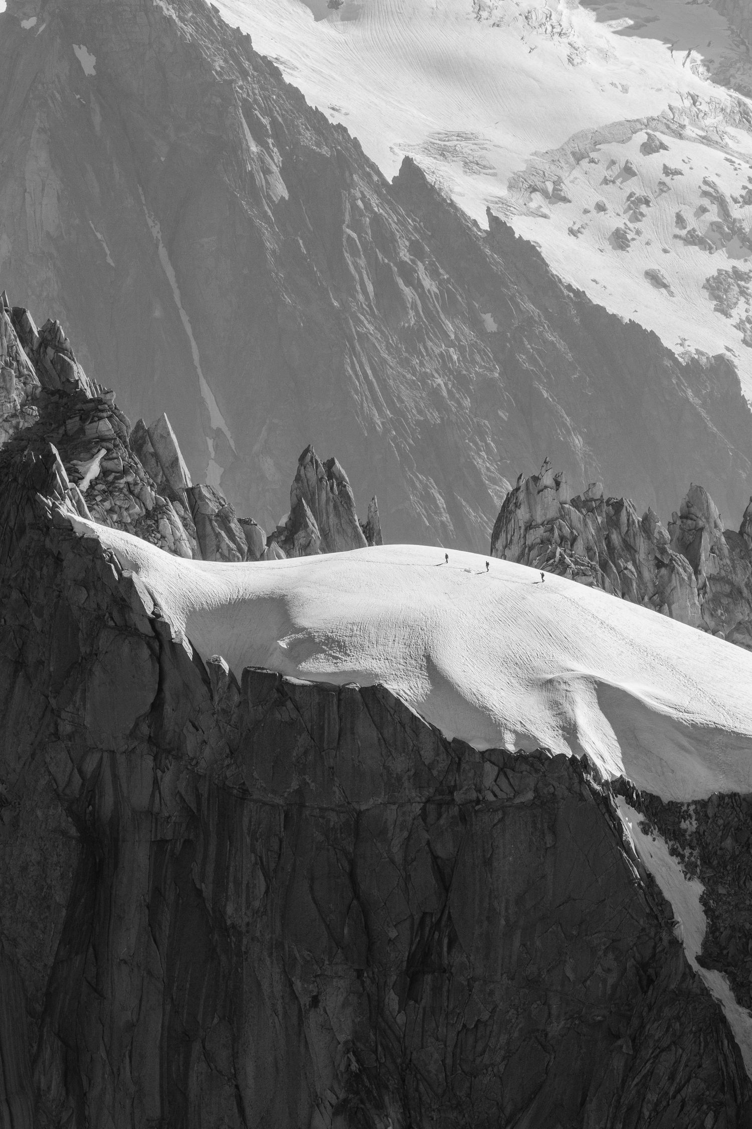 Snow-covered mountain ridge with jagged rock formations in black and white.
