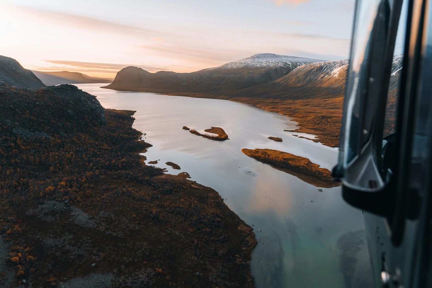 Aerial view of a serene mountain lake reflecting the sunset sky.