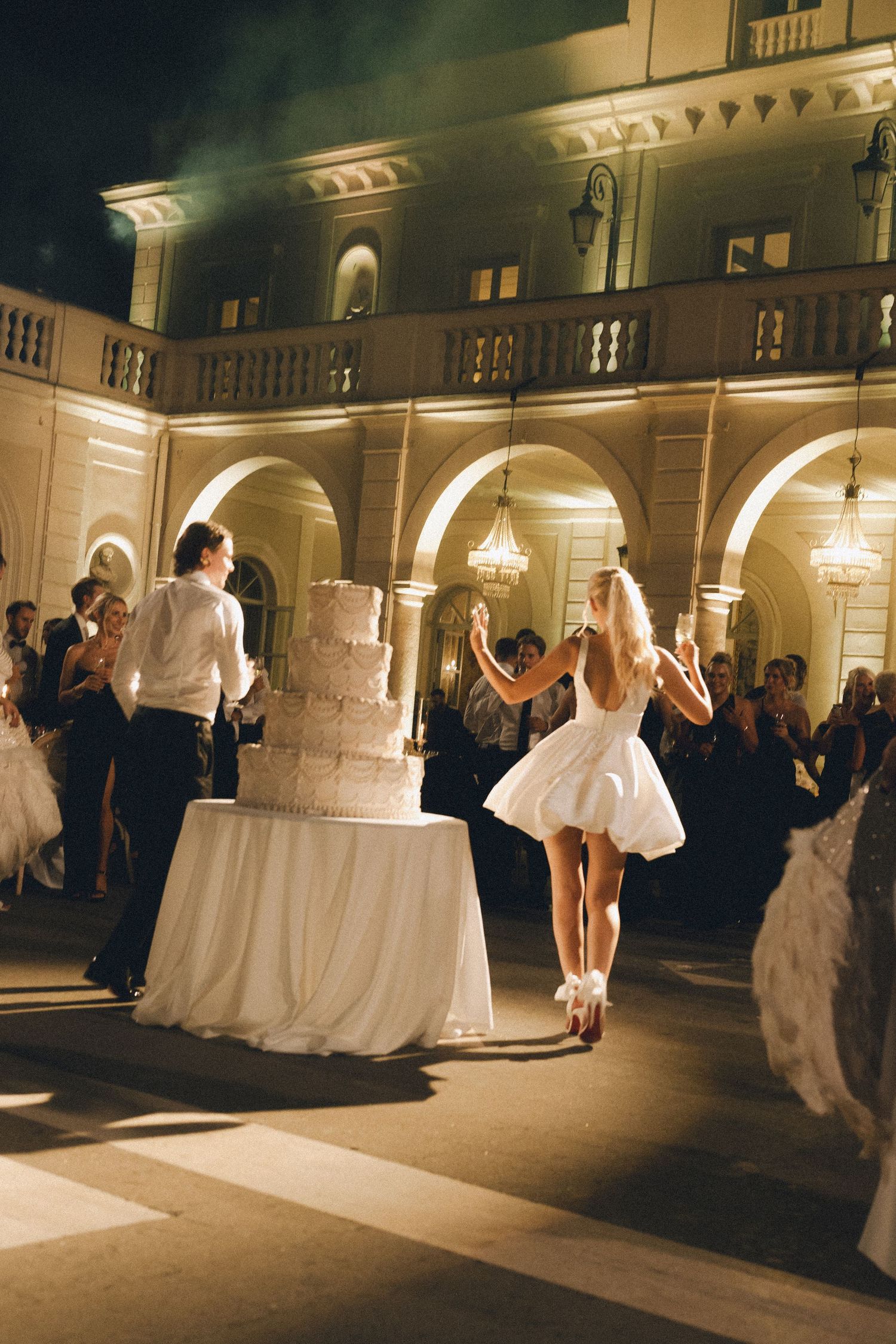 Cake cutting outside on Villa MIani's terrace. Big white traditional wedding cake.