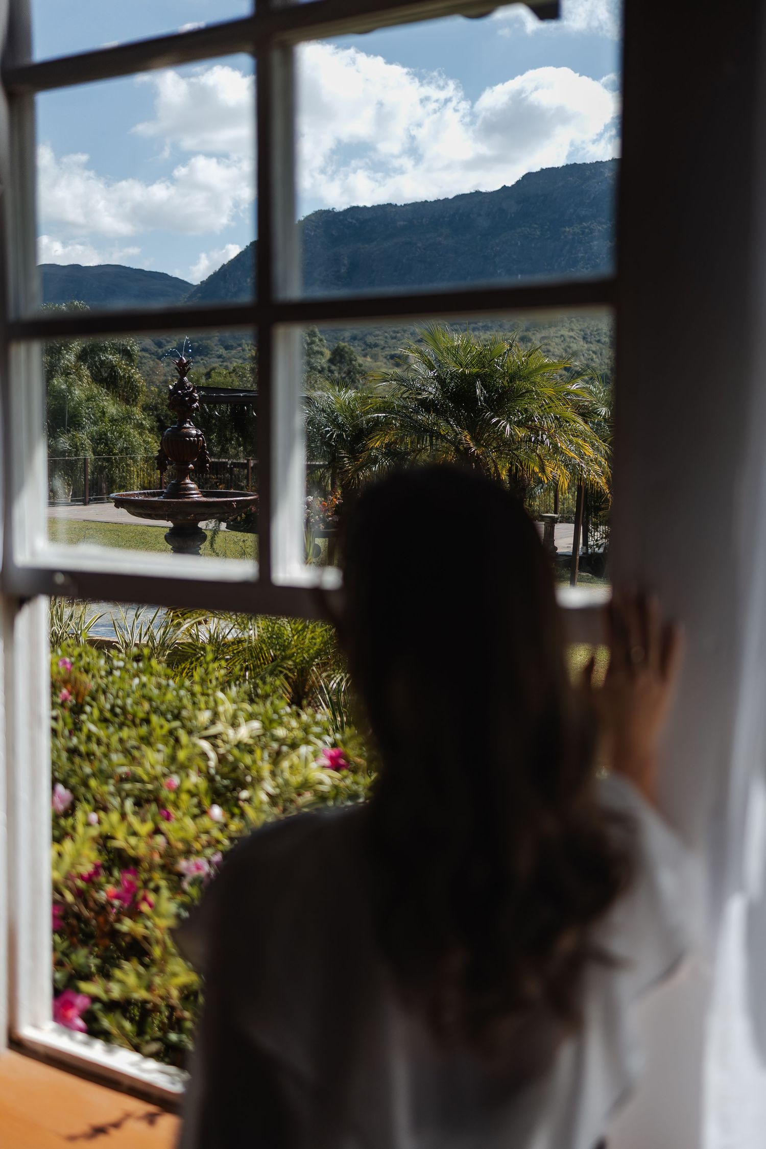 Shadowy figures look through a window at panoramic mountain views and lush tropical gardens in Hawaii.