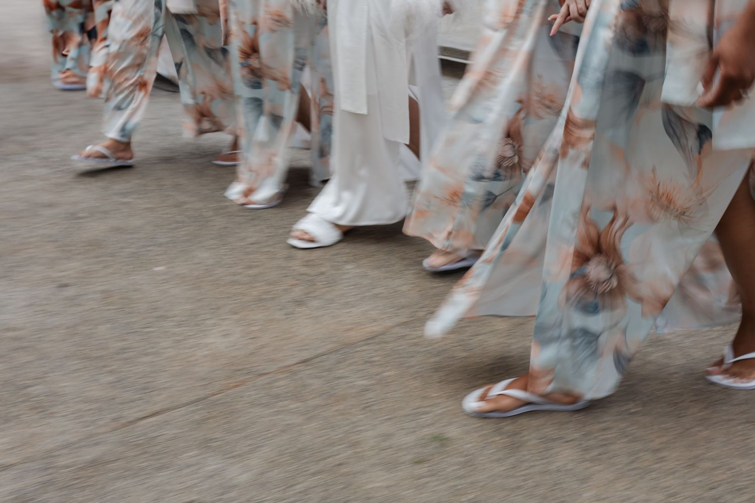 People wearing traditional Japanese yukata with floral patterns walk on a stone street during a festival or celebration.