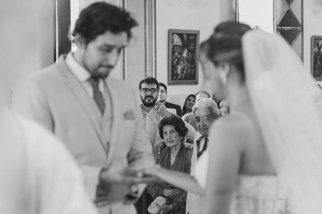A black and white photograph of a wedding ceremony showing a bride and groom exchanging rings at the altar.