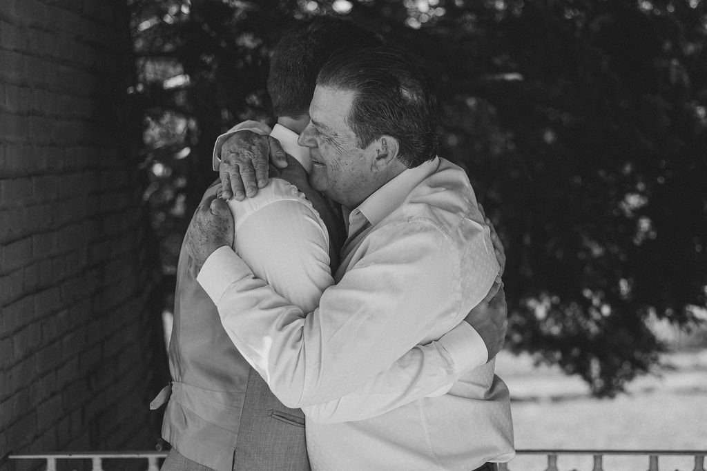 A tender black and white romantic embrace between two people wearing light-colored clothing outdoors.