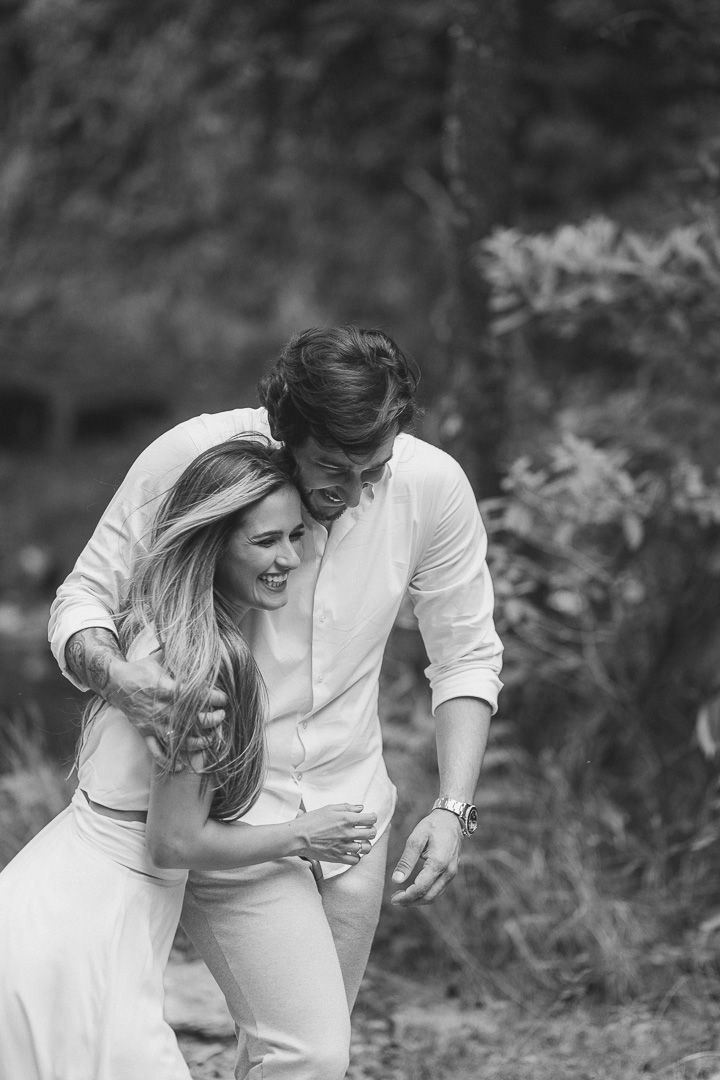 A couple in white outfits share a tender moment outdoors in black and white photography.