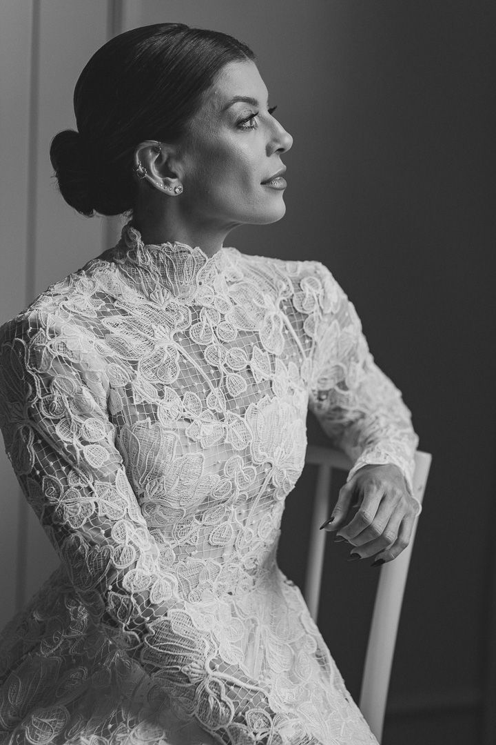 Side profile black and white portrait of someone in an elegant white lace wedding dress with high neckline and delicate details.
