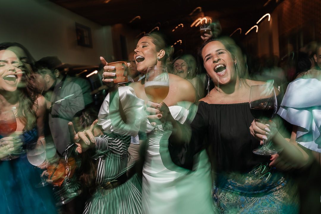 A group of partiers laughing and celebrating at a lively event with drinks in their hands.