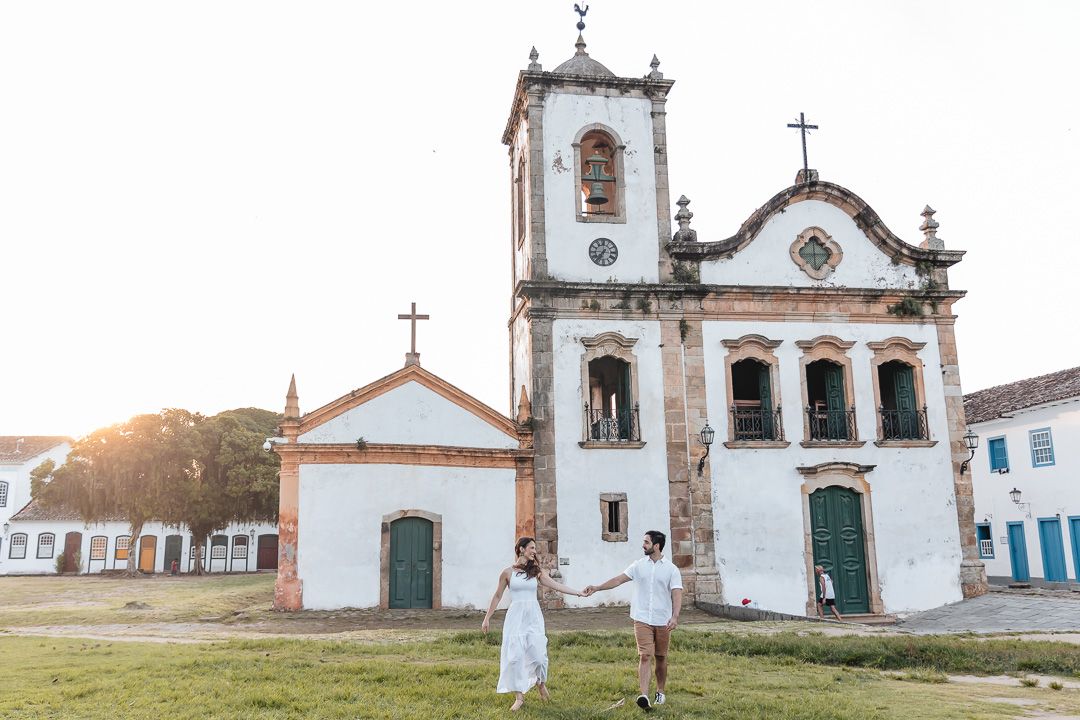 White colonial church building with dramatic sunset lighting in Paraty, Brazil during golden hour.