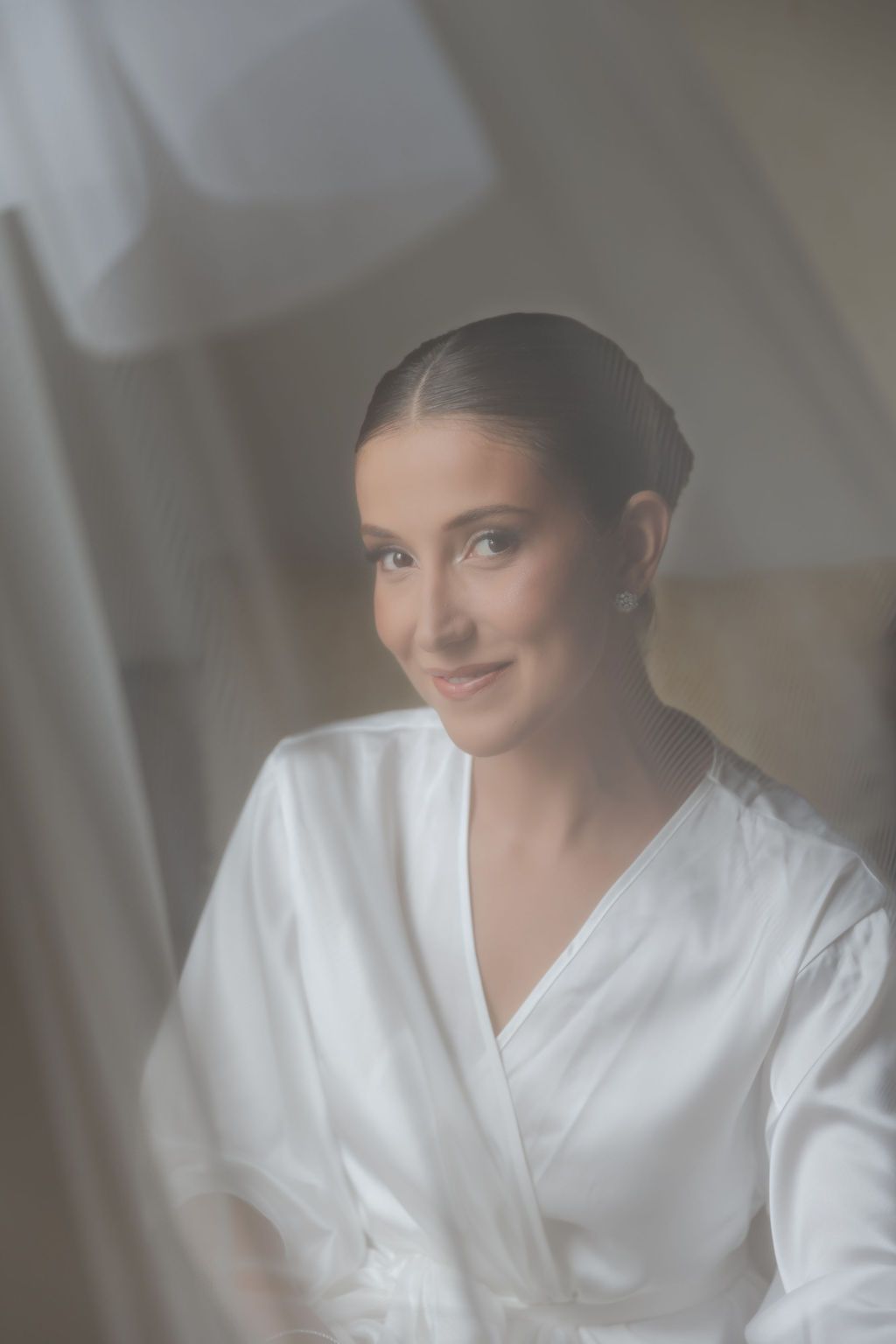 Cerimônia de casamento ao ar livre na FaA person wearing a white bathrobe smiles warmly while being photographed in soft, diffused lighting.