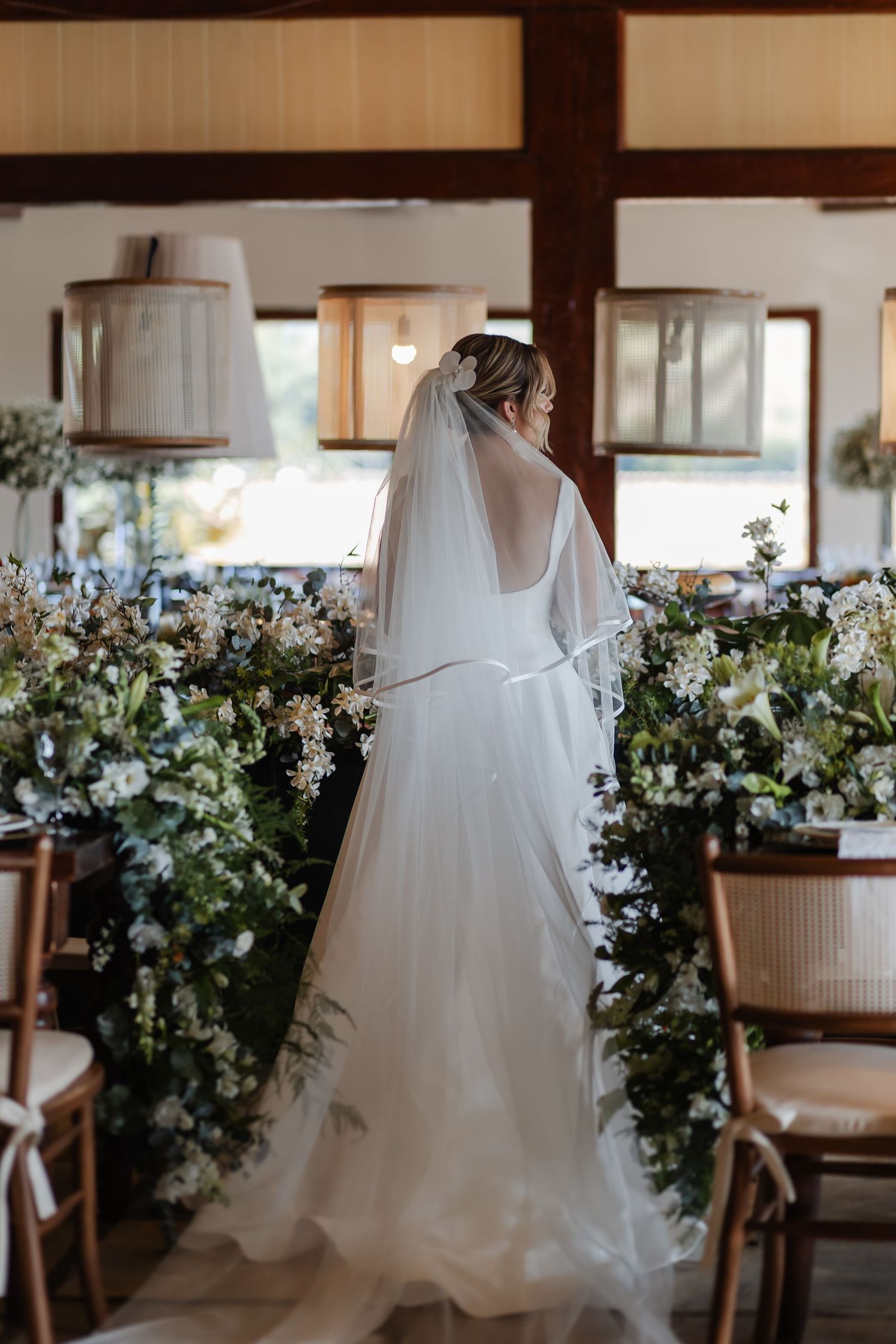 Wedding dress displayed with floral arrangements and white decor in an elegant venue setting.