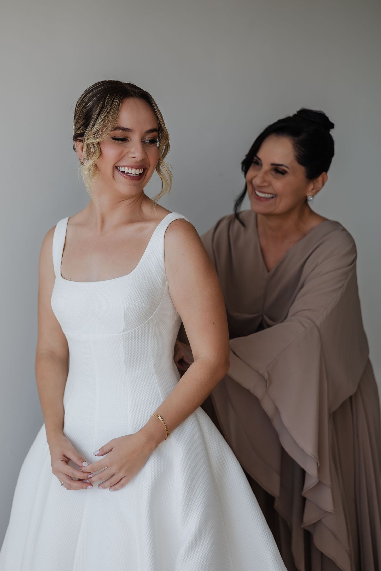 A series of candid studio portraits showing warm interactions and genuine laughter against a grey background.