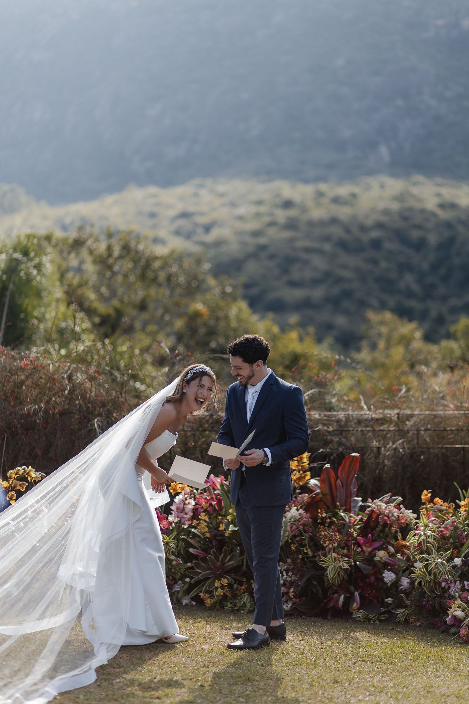 A romantic wedding couple shares a tender moment together in a scenic mountain garden setting with colorful flowers.