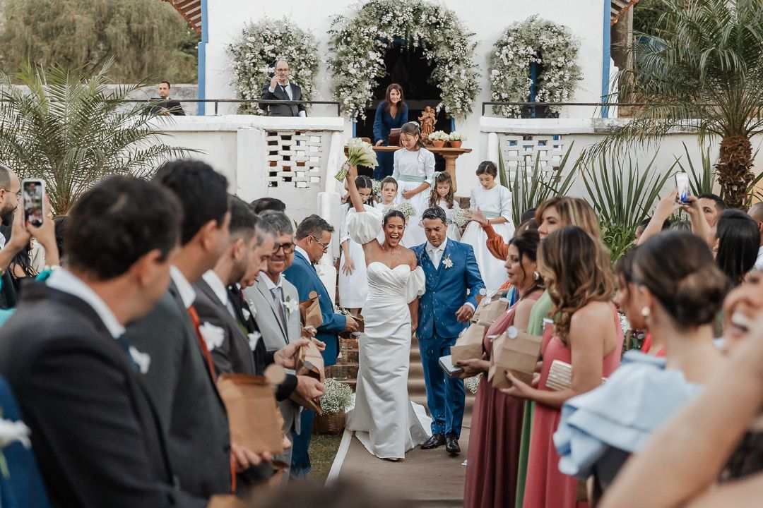Wedding party gathers on outdoor steps with palm trees and white architecture during tropical ceremony celebration.
