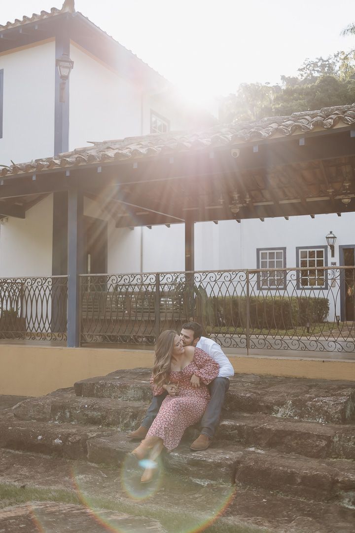 Two figures embracing on stone steps outside a colonial style building with sun flare in Ouro Preto, Brazil.