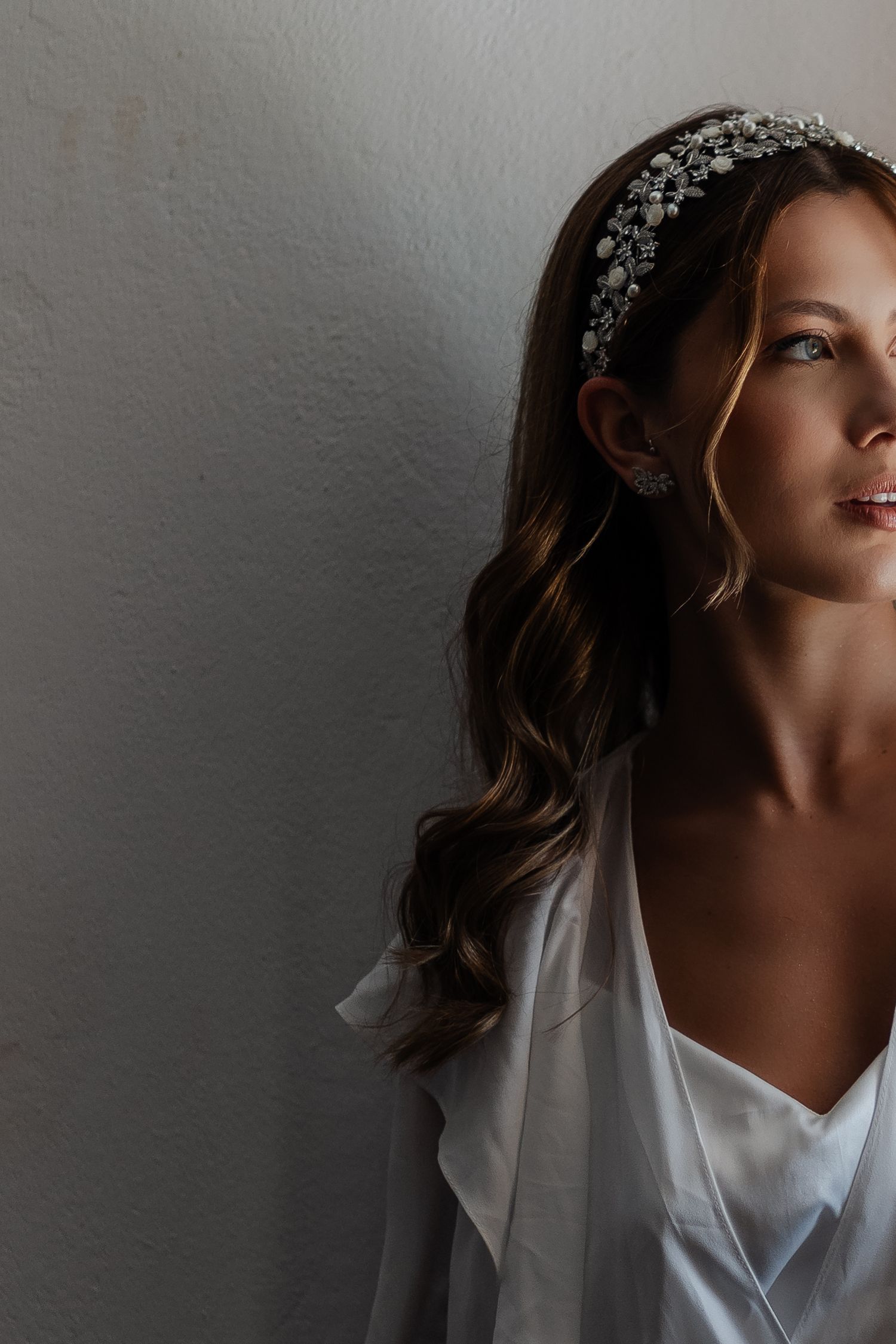 A dramatic side profile portrait shows a figure wearing a white top and delicate headpiece against a gray backdrop.