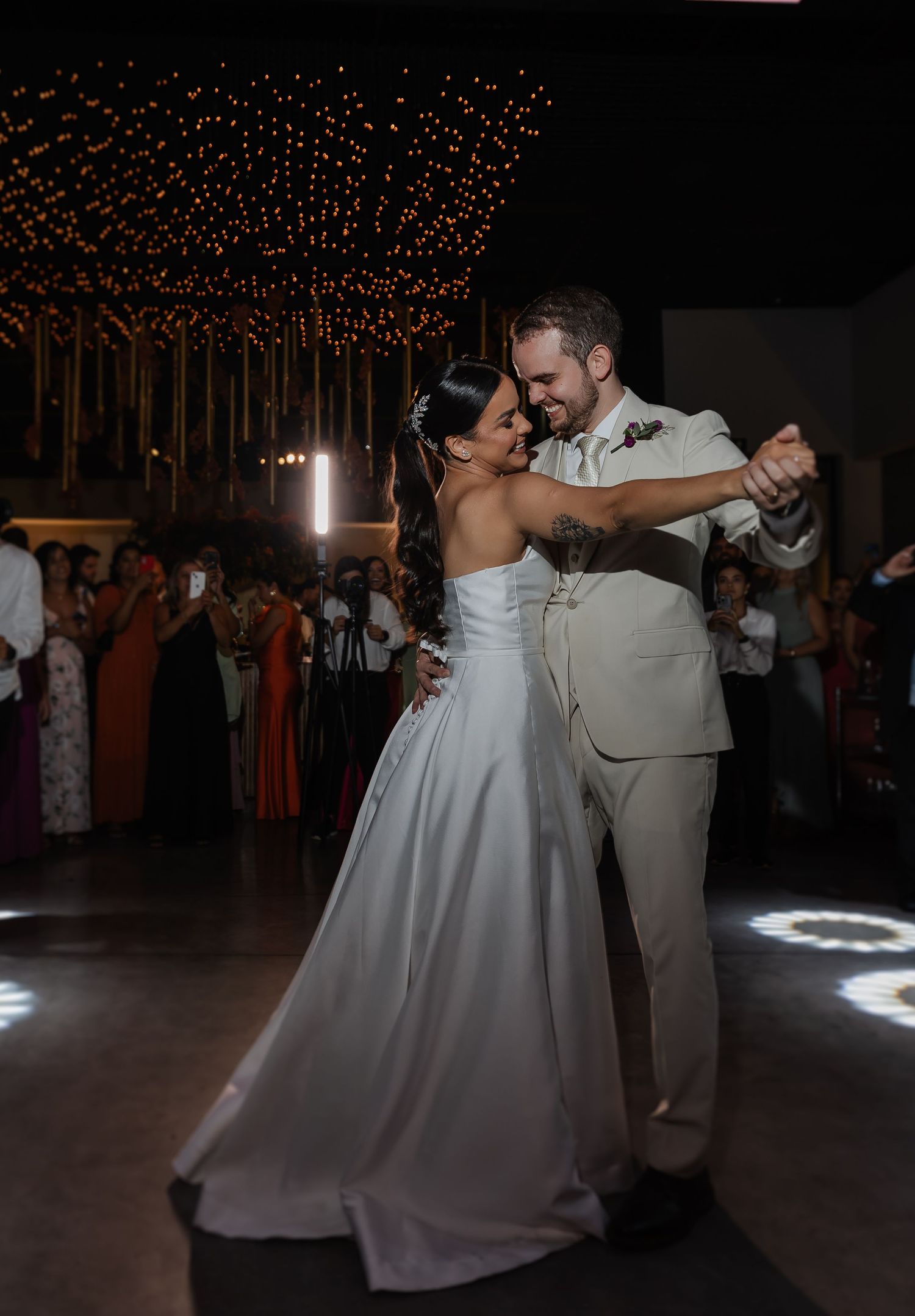 A romantic first dance between a couple at their wedding reception under soft lighting and sparkling decorations.