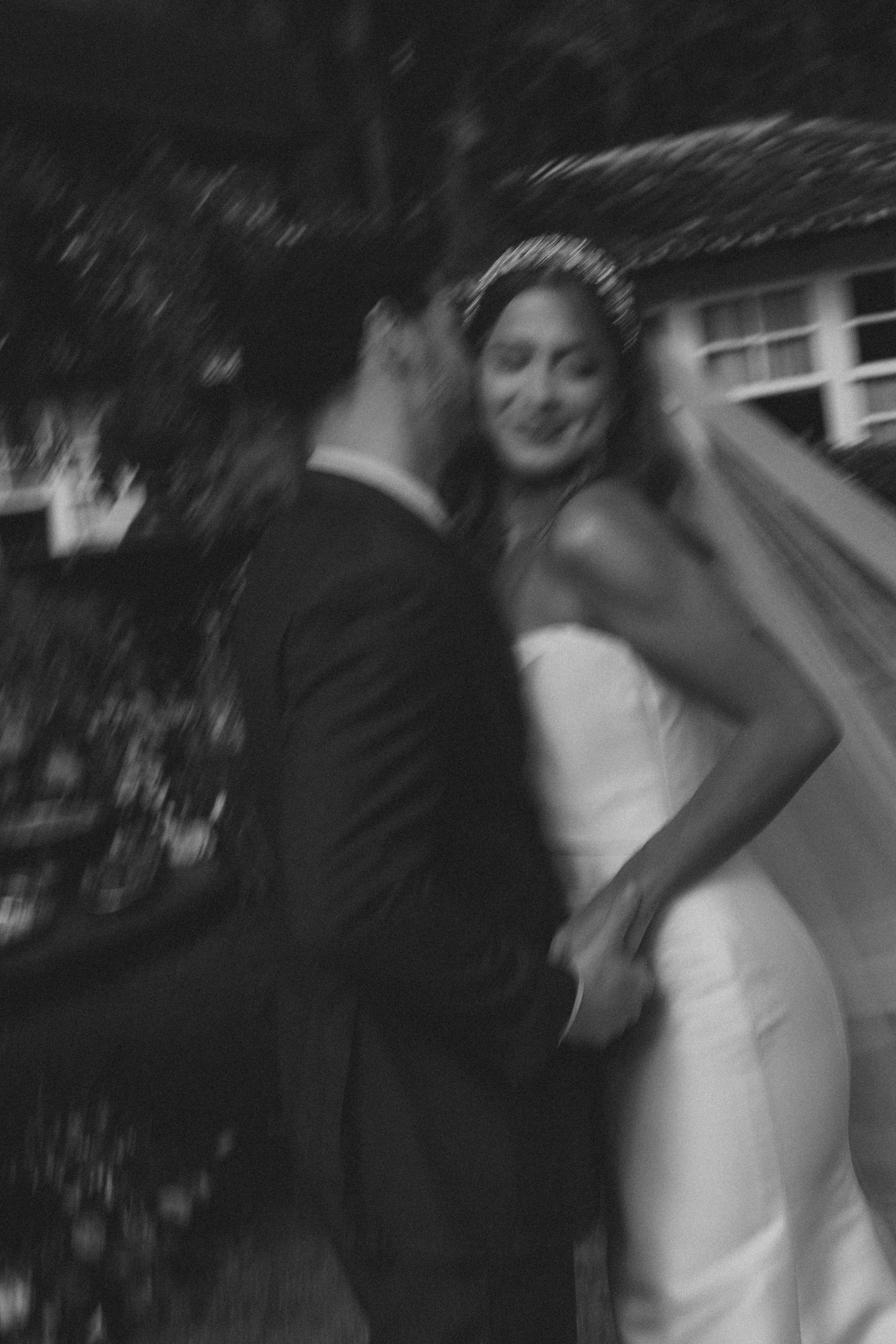 Black and white photo captures a blurry dance sequence showing movement and motion between dancers at a formal event.