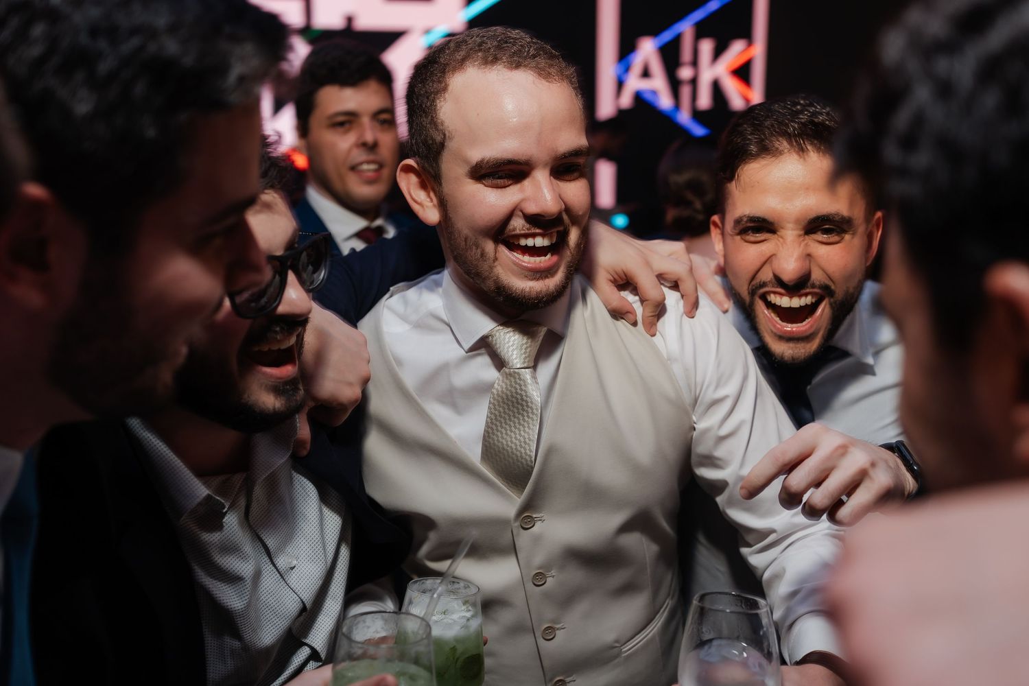 A group of joyful friends celebrating at a nightclub party with drinks and laughter.