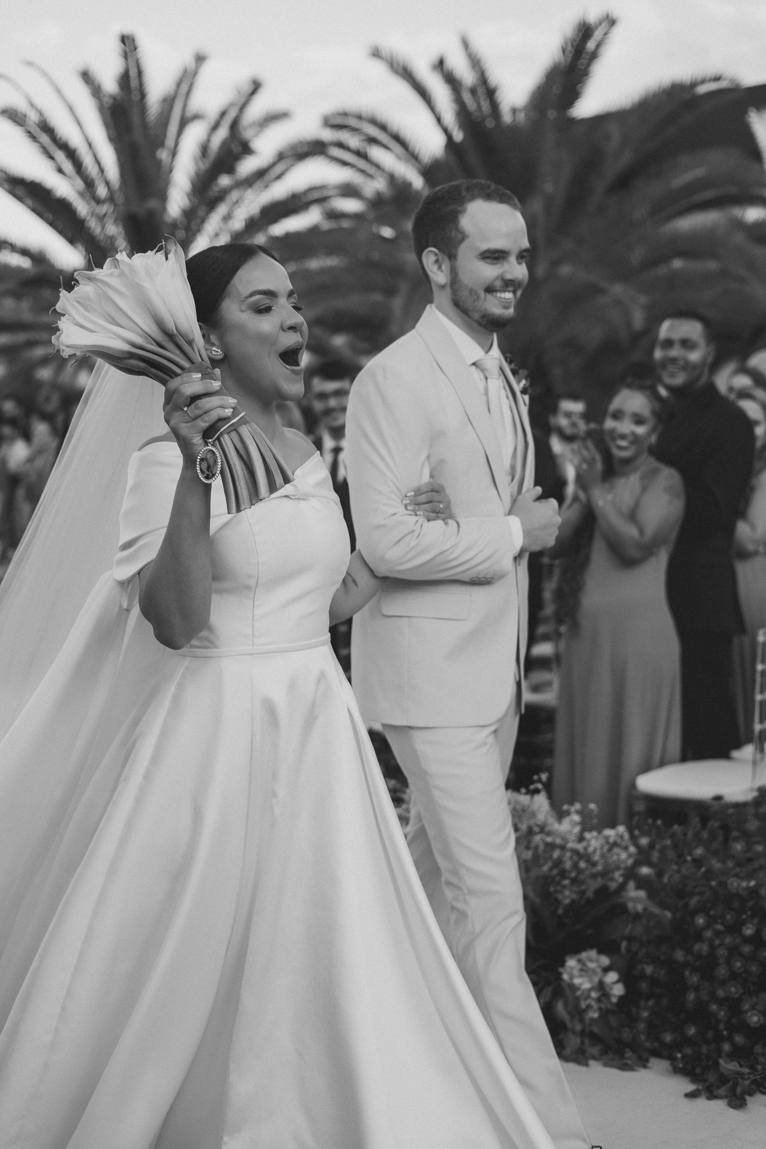 Joyful moment at an outdoor wedding celebration as newlyweds embrace and dance together in classic white attire.