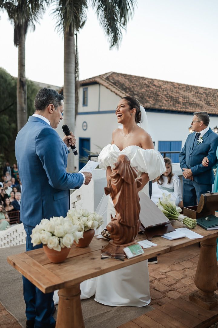 Wedding ceremony at historic chapel featuring couple exchanging vows at wooden altar with white floral arrangements.