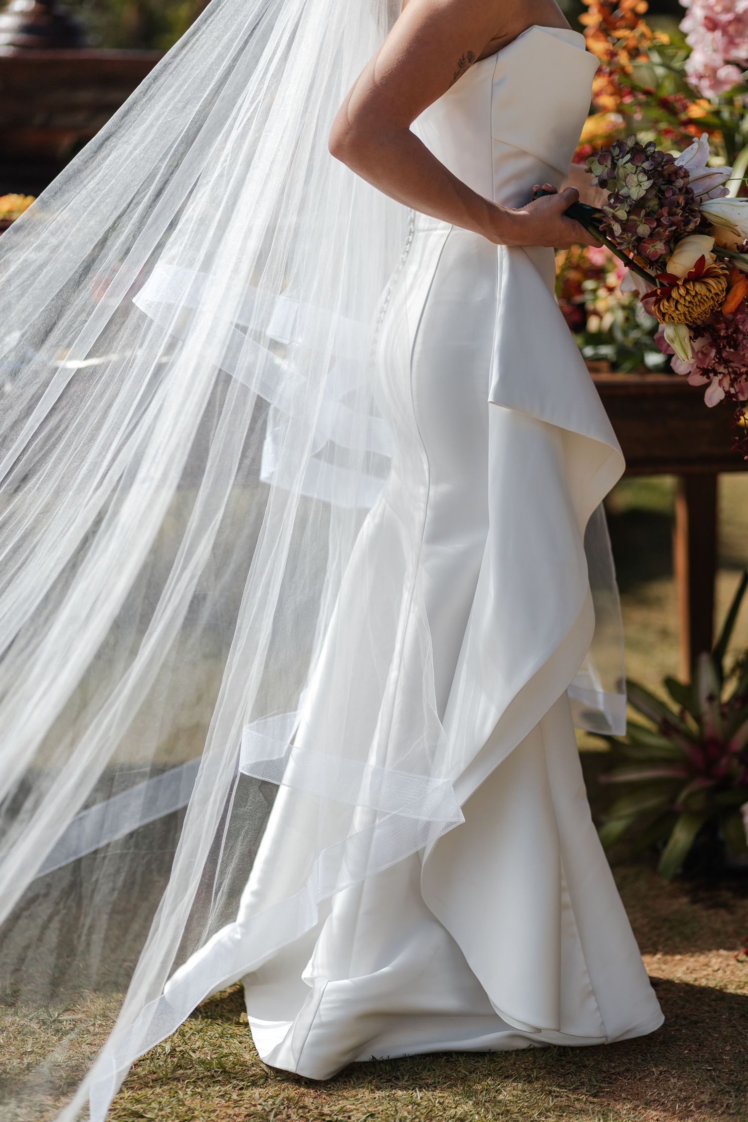 Close-up details of white wedding dress layers with flowing tulle fabric cascading in elegant ruffles.